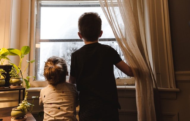 Junge und Mädchen stehen am Fenster | Quelle: Unsplash
