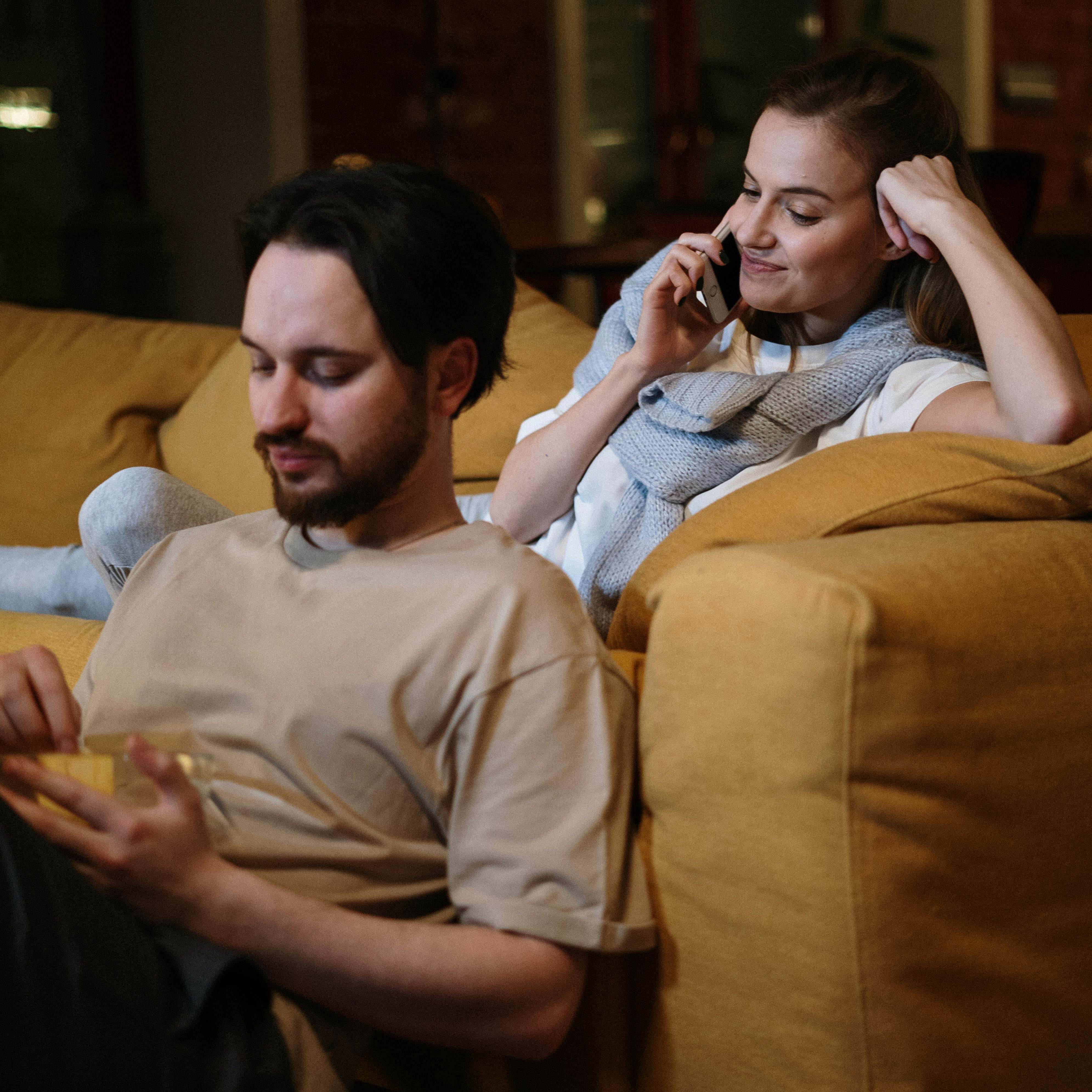 A woman making a phone call with a man sitting companionably nearby | Source: Pexels