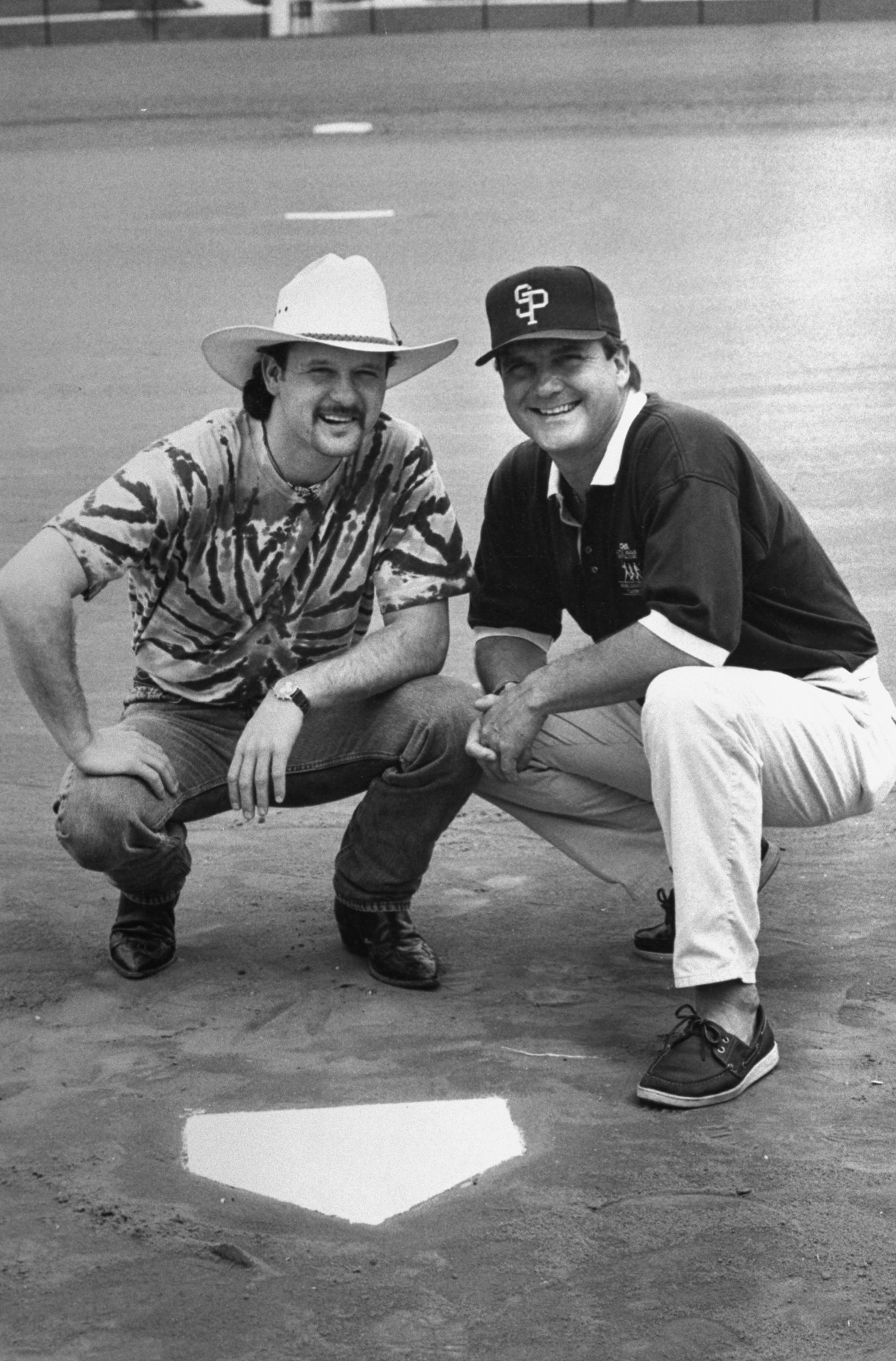 Tim McGraw w. father, former baseball player Tug McGraw in baseball cap, as they crouch next to home plate on baseball field. | Source: Getty Images