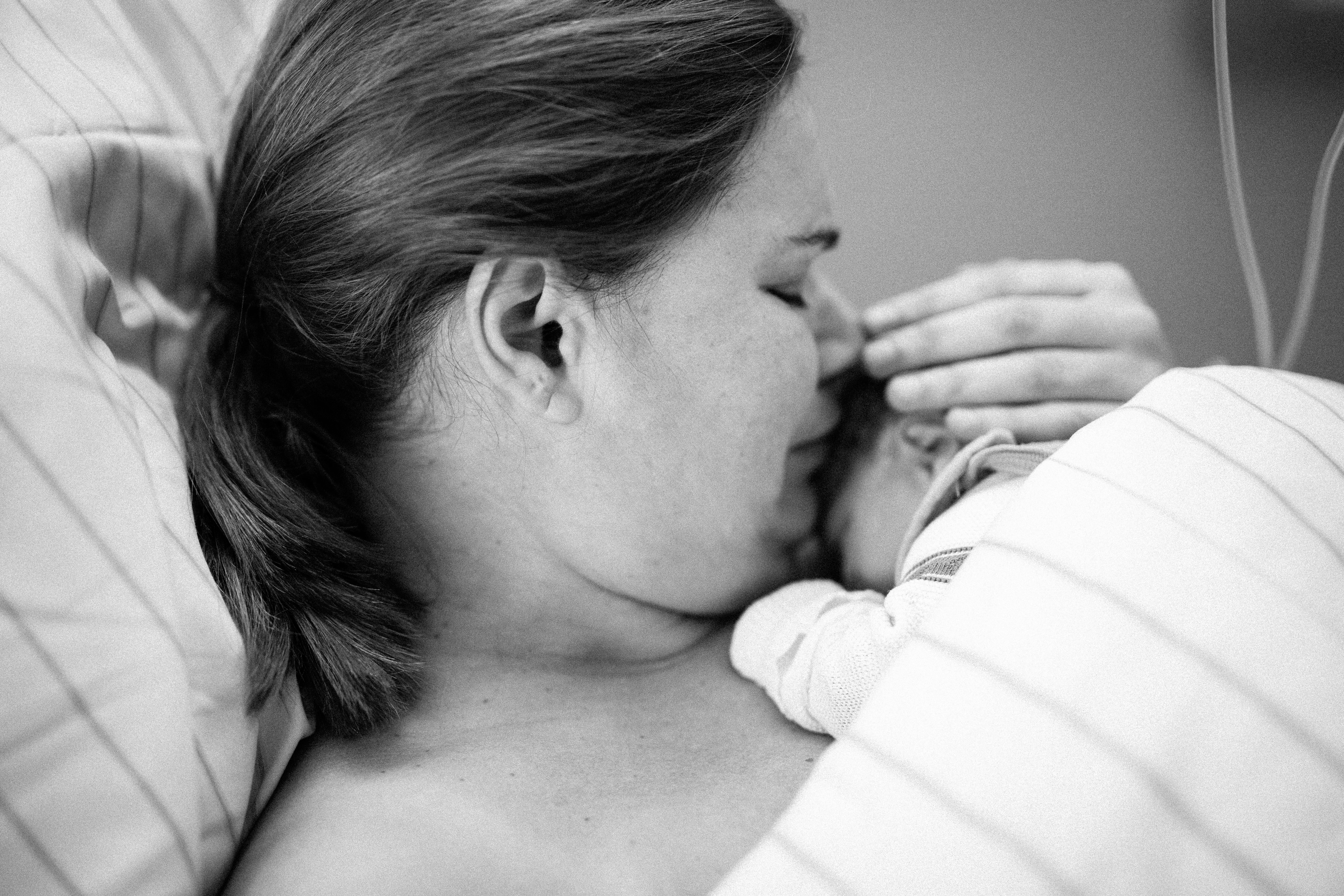 A mother kissing her newborn baby | Source: Shutterstock