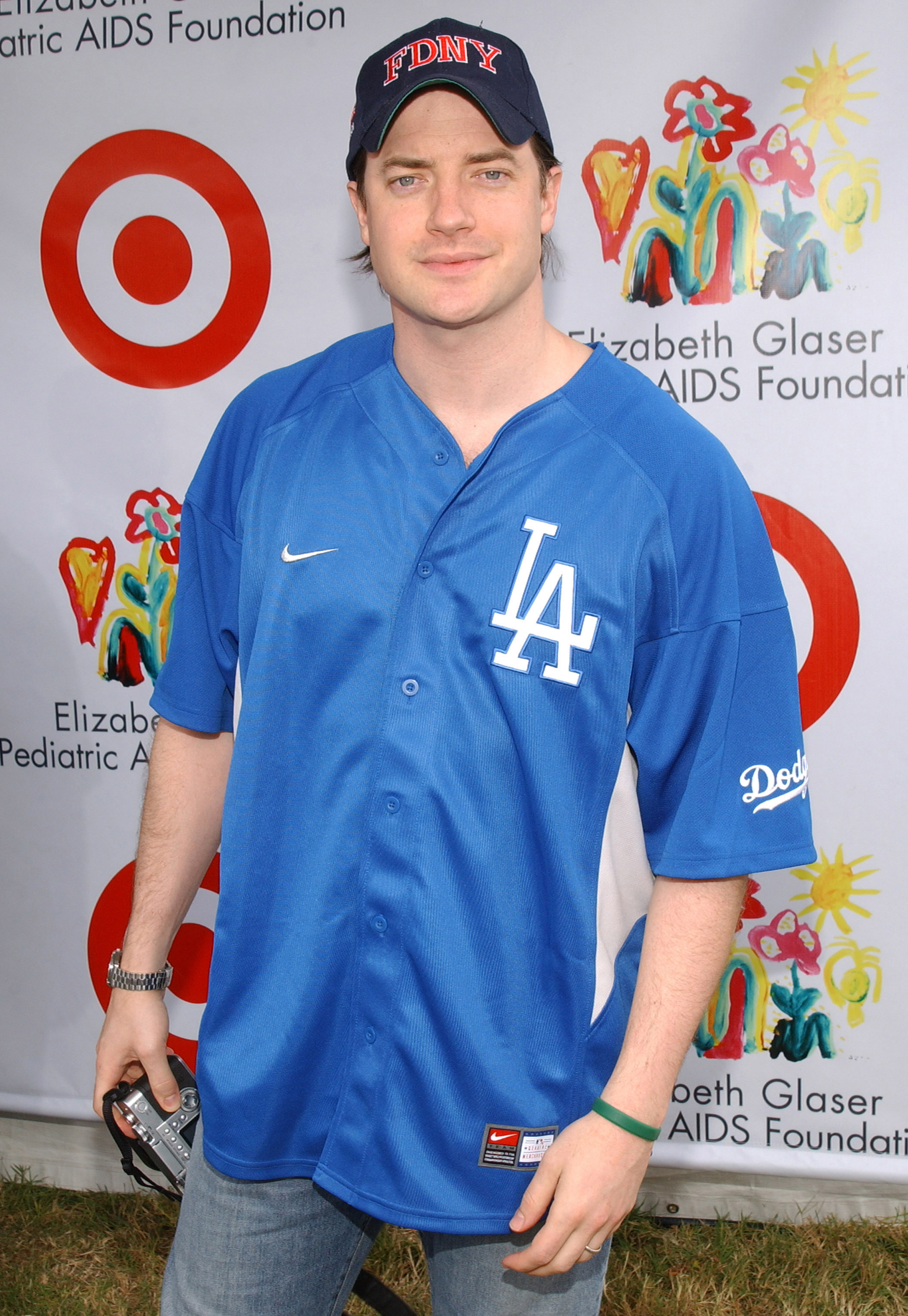 Brendan Fraser wears a blue Los Angeles Dodgers jersey, jeans, and an FDNY cap while arriving at the Elizabeth Glaser Pediatric AIDS Foundation's "A Time for Heroes" Celebrity Carnival in Los Angeles.