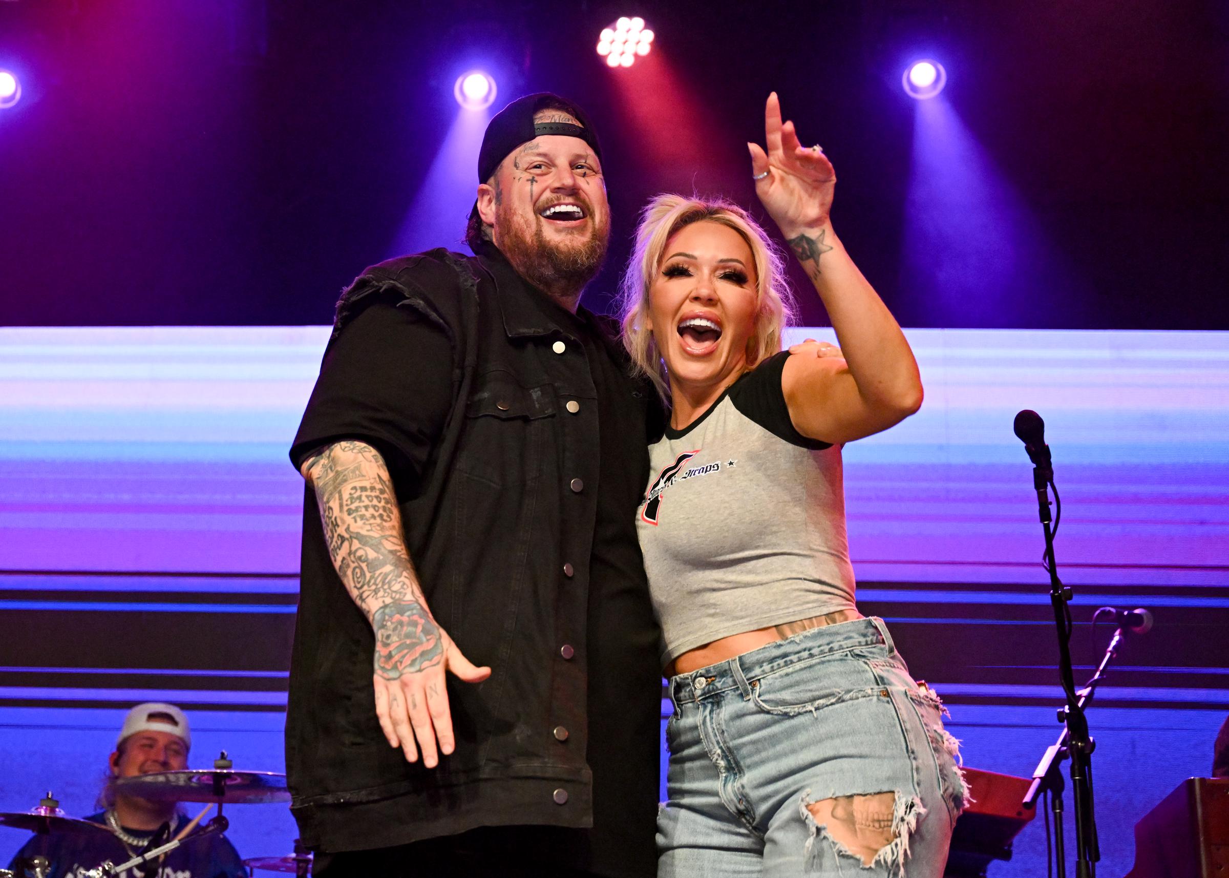 Jelly Roll and Bunnie XO smile and embrace onstage during a live performance, appearing in high spirits under colorful stage lights. The photo resurfaced as a source claimed the former couple, who are divorcing after nearly a decade of marriage, "still love each other." | Source: Getty Images