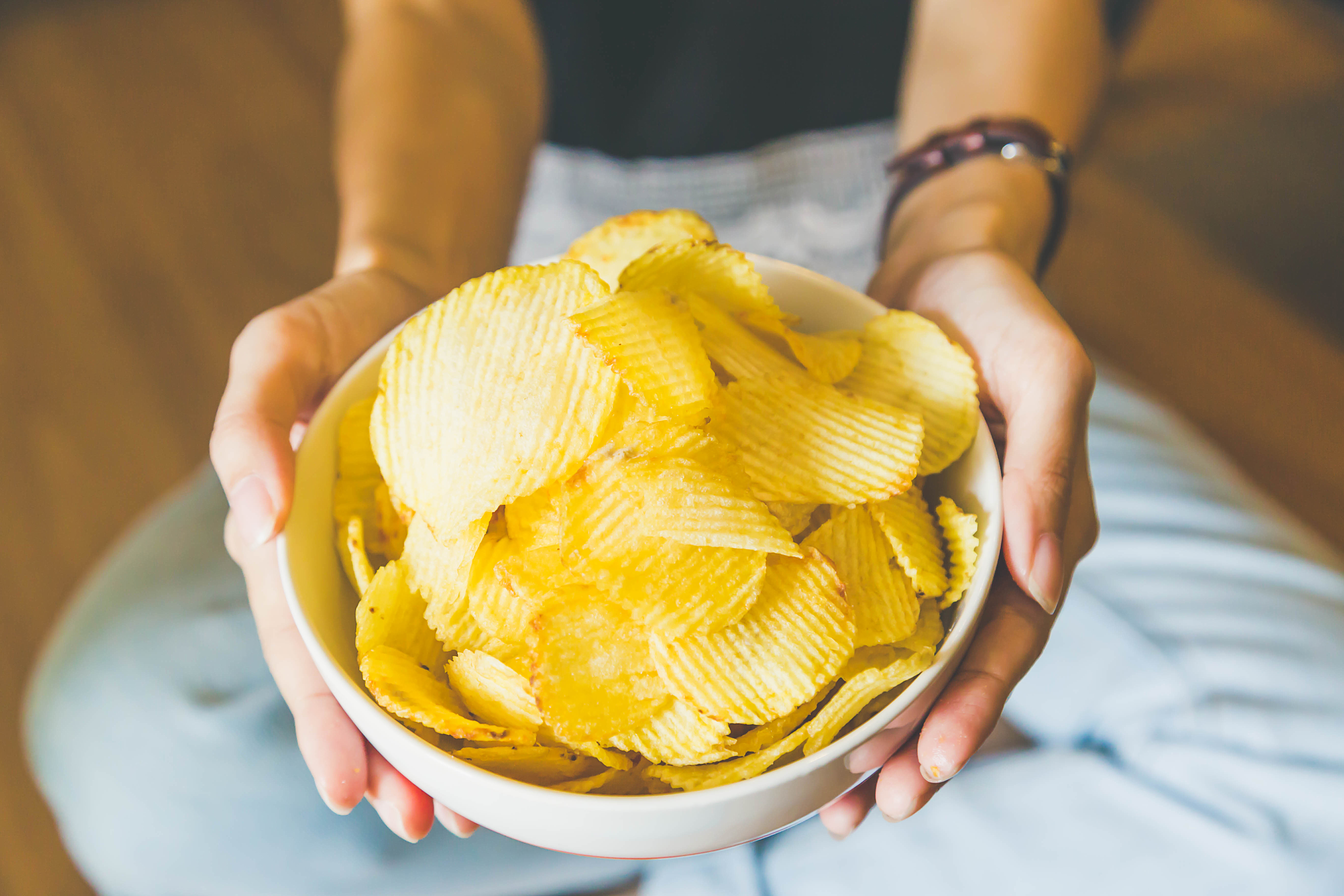 A person holding a bowel of potato chips | Source: Shutterstock