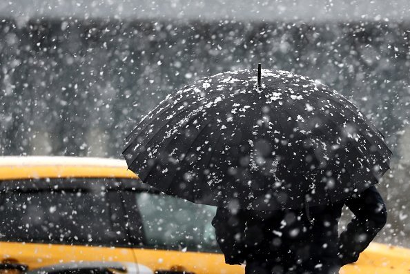 Photo of a man standing a taxi during a heavy snowfall | Photo: Getty Images