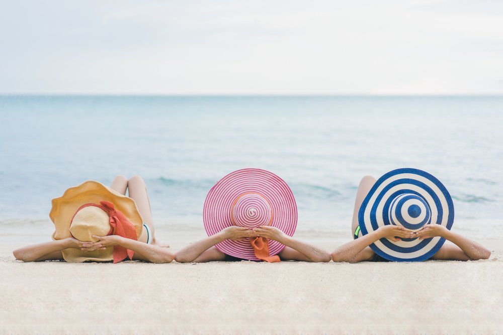 A photo of three woman on a beach discussing. | Photo: Getty Images.