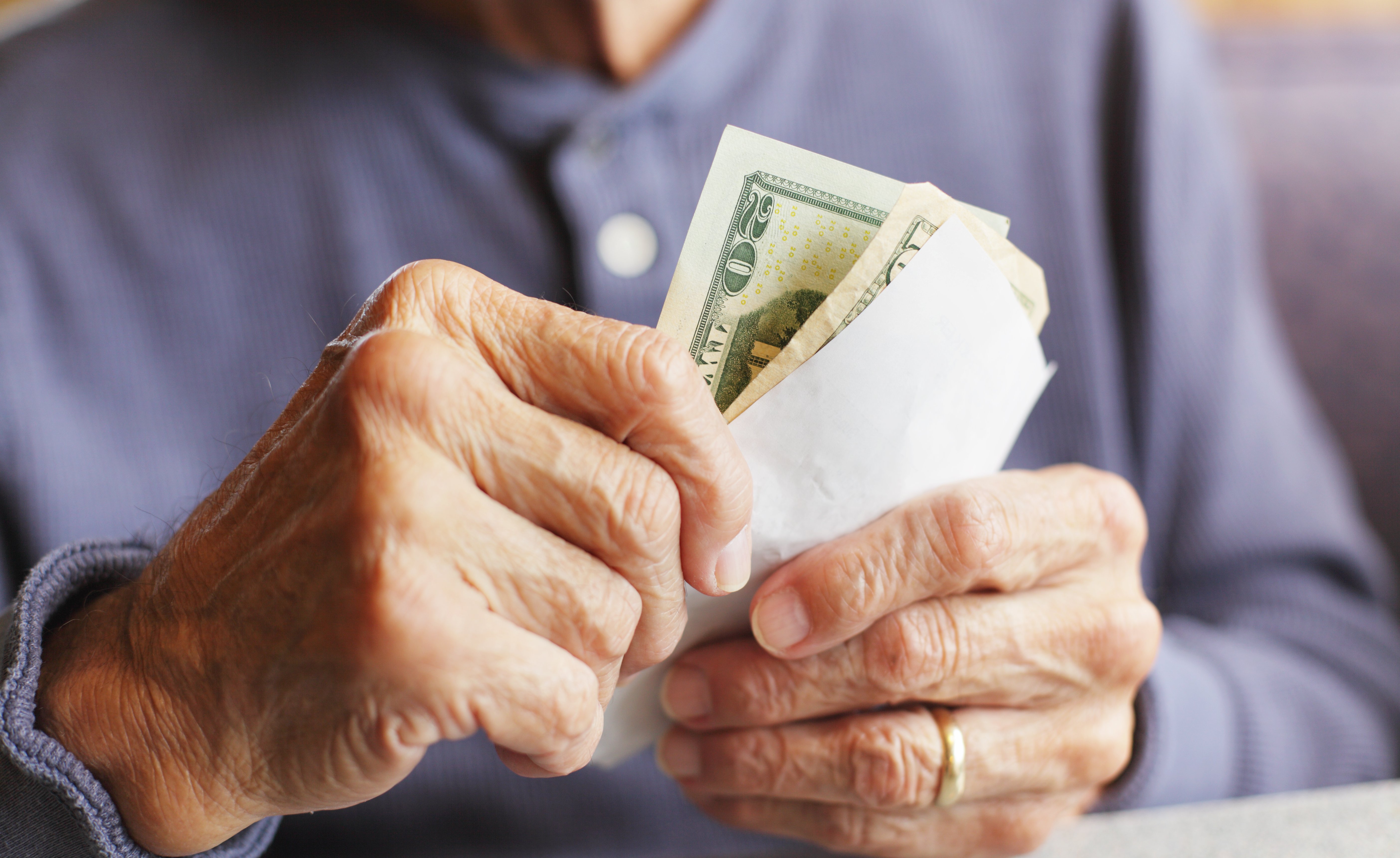 An older man holding money while sitting at a restaurant table. | Source: Getty Images