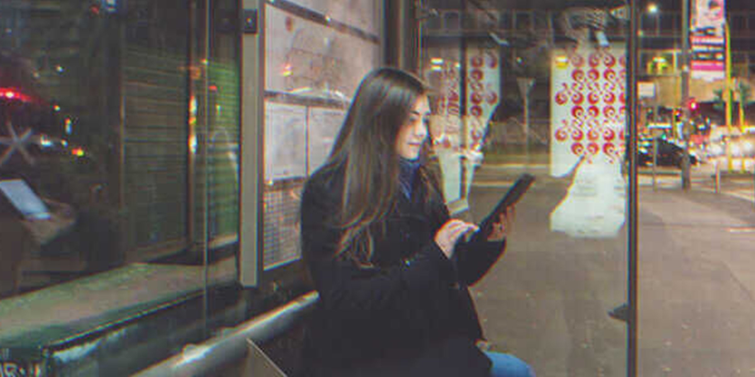 A girl looking at a tablet on a bus stop | Source: Shutterstock