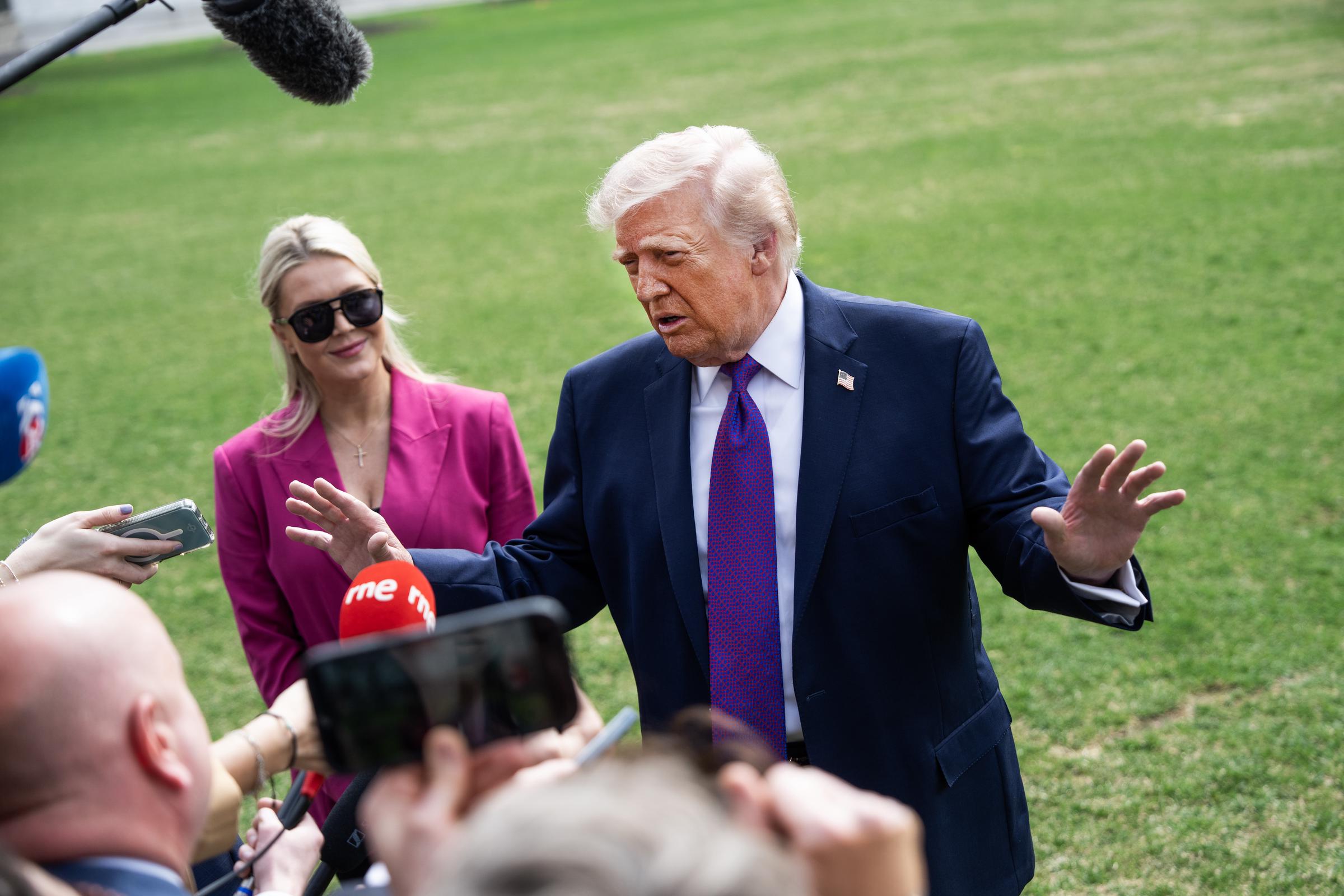 Donald Trump speaks to reporters alongside Karoline Leavitt as he departs for Marine One on the South Lawn of the White House on March 11, 2026 in Washington, DC | Source: Getty Images