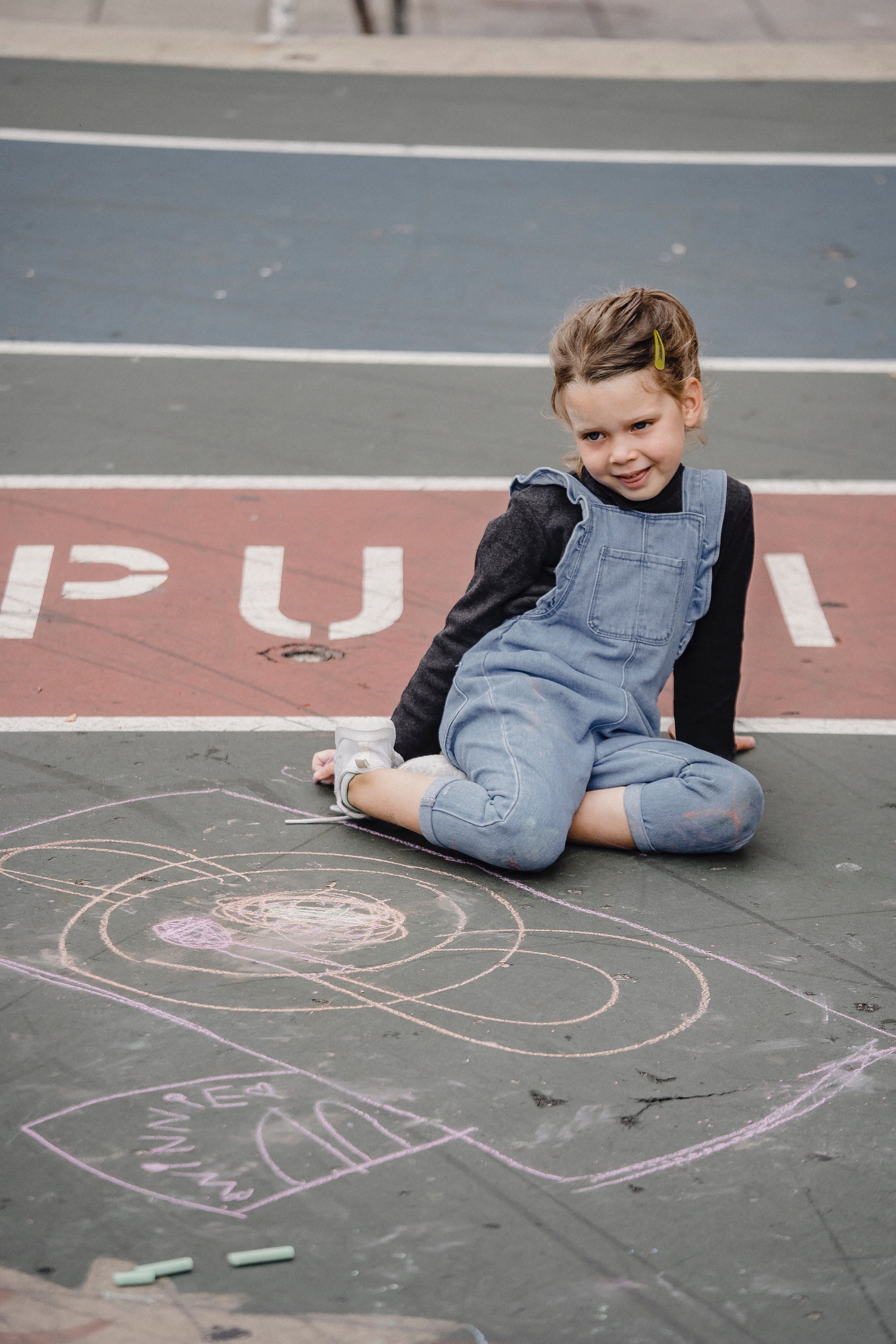 Pictured - A young girl sitting on asphalt neat chalk painting | Source: Pexels 