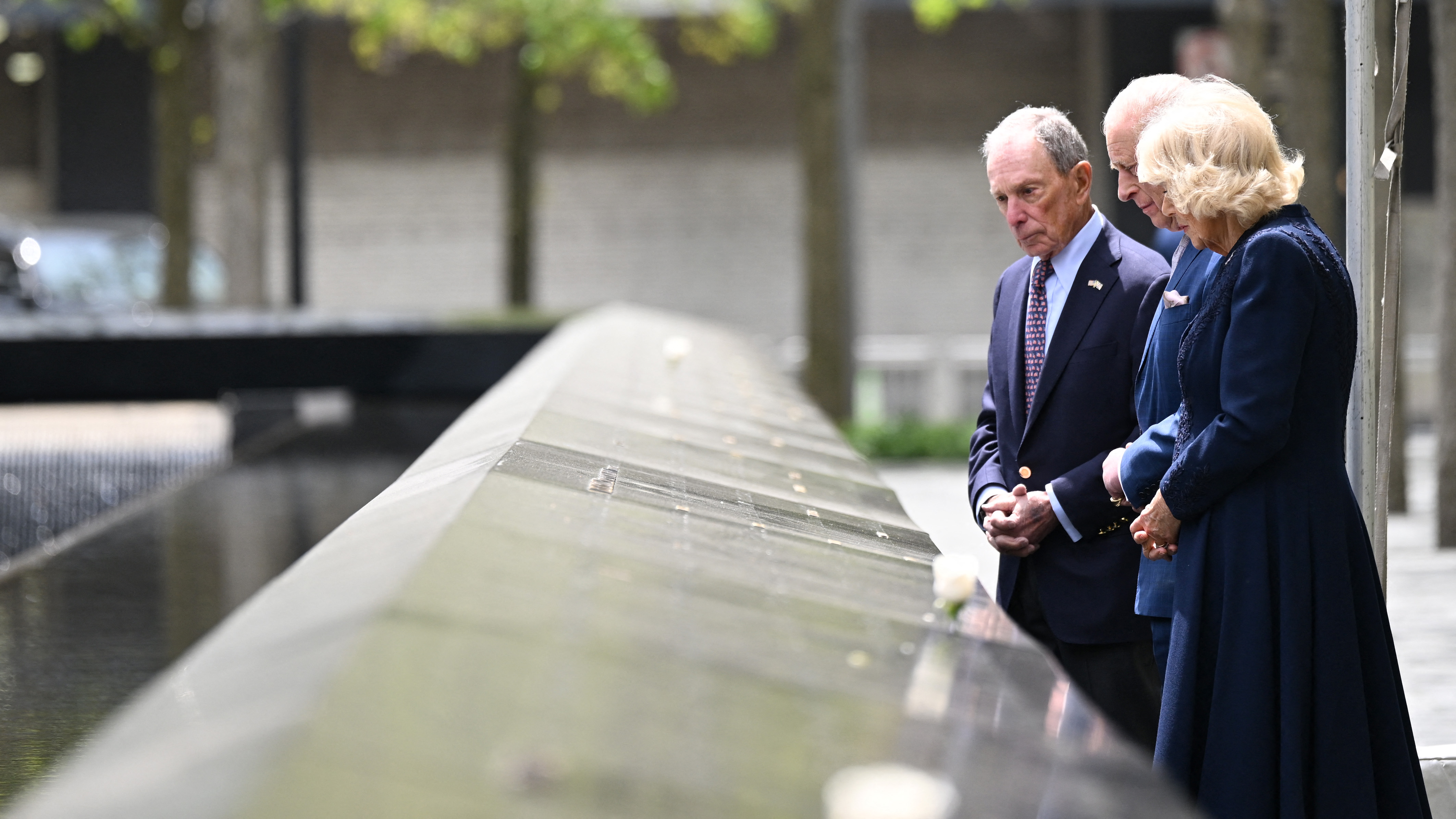 King Charles III and Queen Camilla stand with Michael Bloomberg at the reflecting pool during their 9/11 Memorial visit in New York City | Source: Getty Images