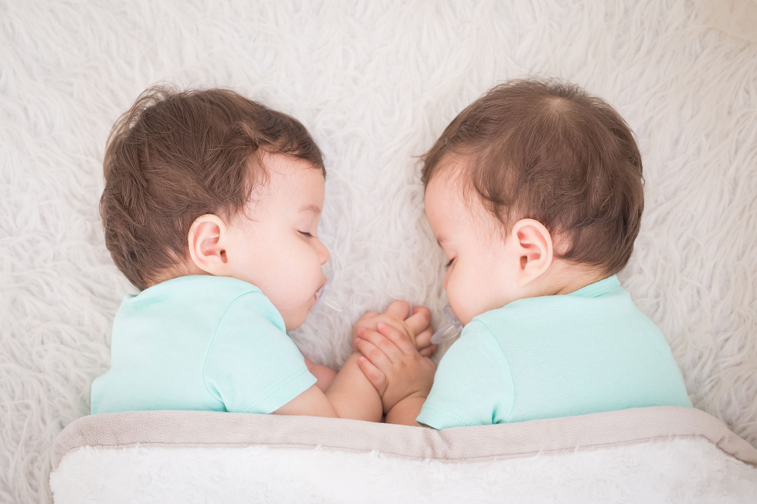 Hermosos gemelos recién nacidos durmiendo con un pacificador. | Foto: Shutterstock
