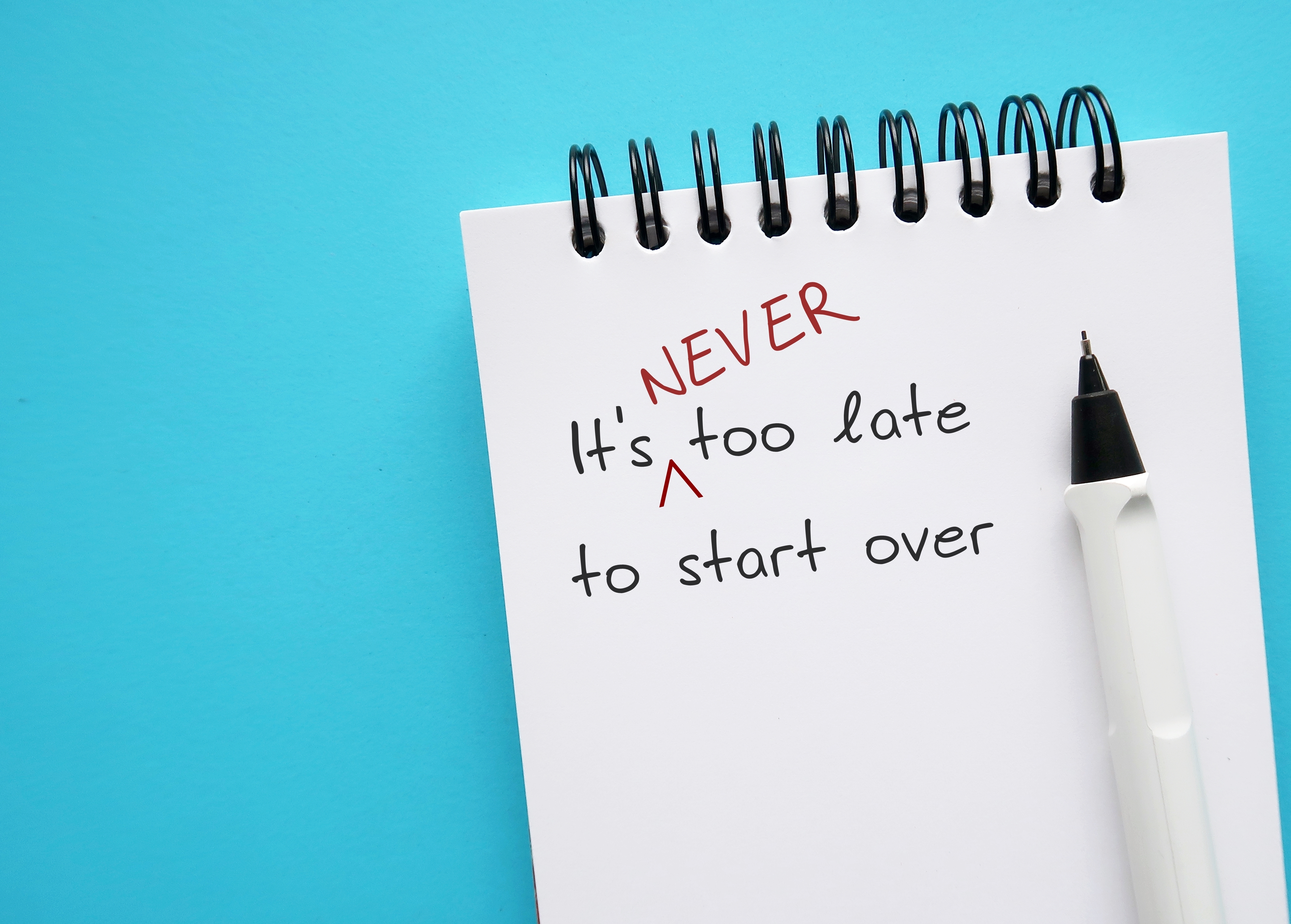 A notebook with the words "It's never too late to start over" scribbled on a page | Source: Shutterstock