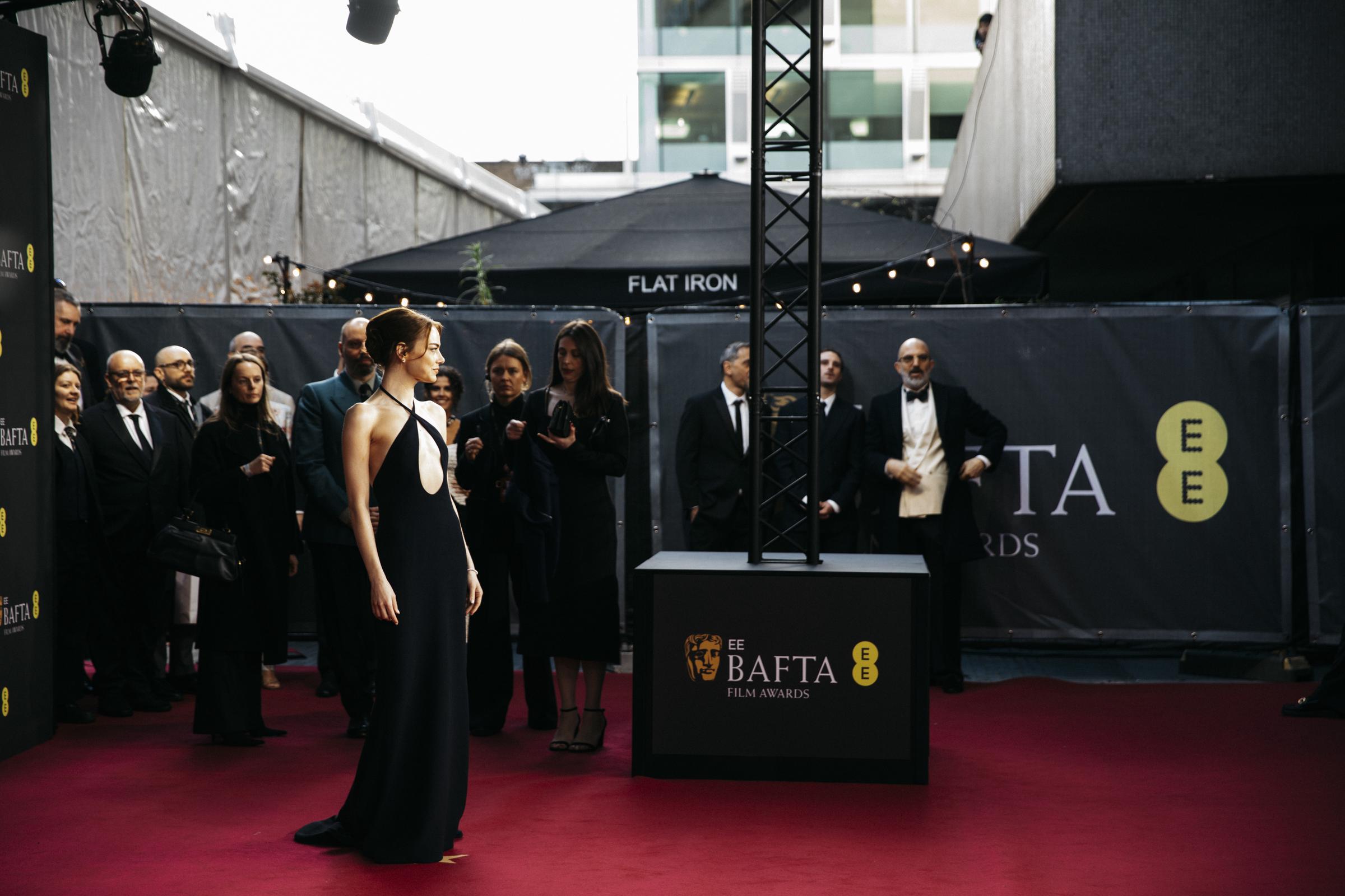 Emma Stone stands poised at roaming arrivals, the dramatic oval cutout and fluid silhouette immediately drawing focus as photographers and guests look on from behind the scenes.