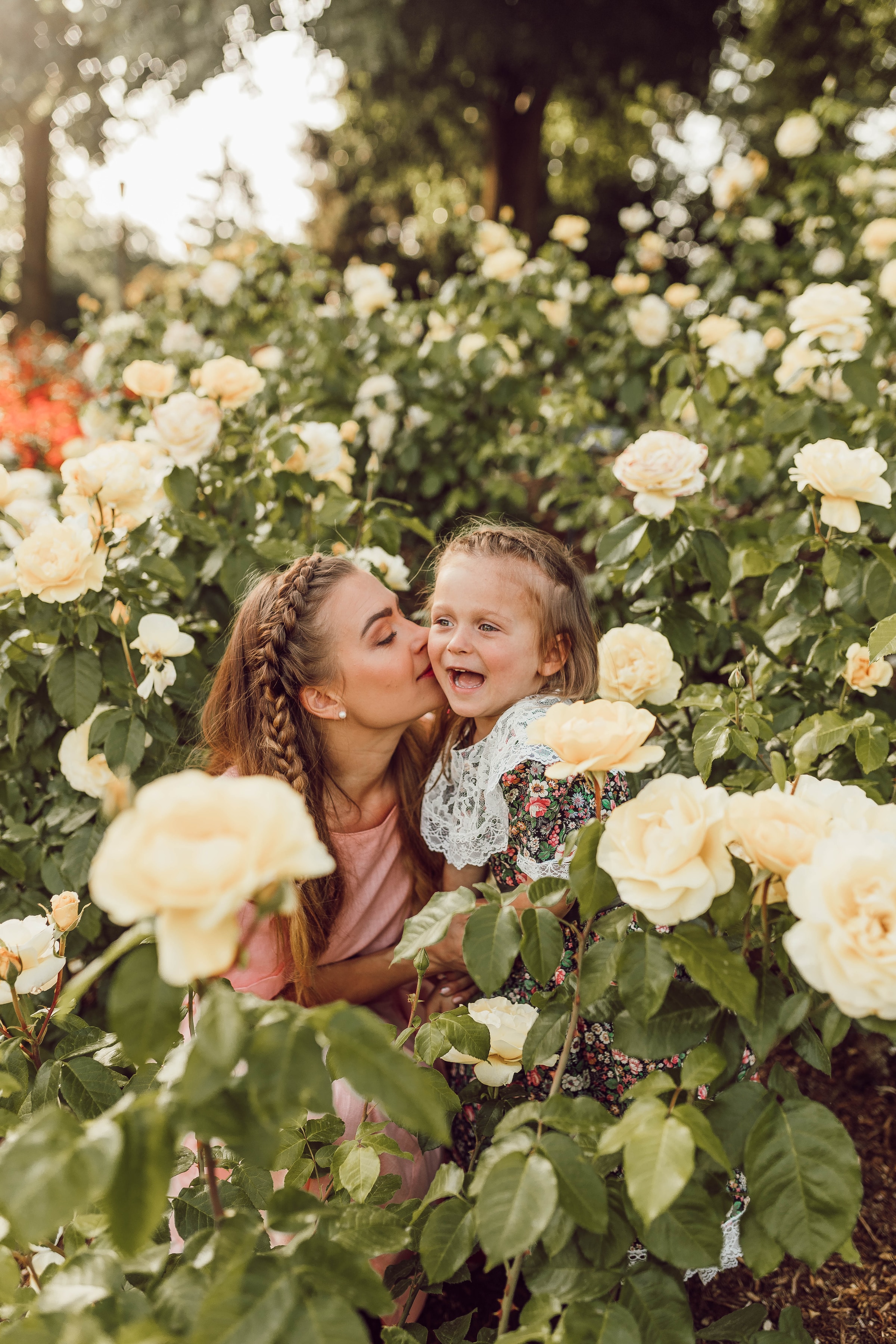 An affectionate mom kissing her little girl in a garden | Source: Shutterstock