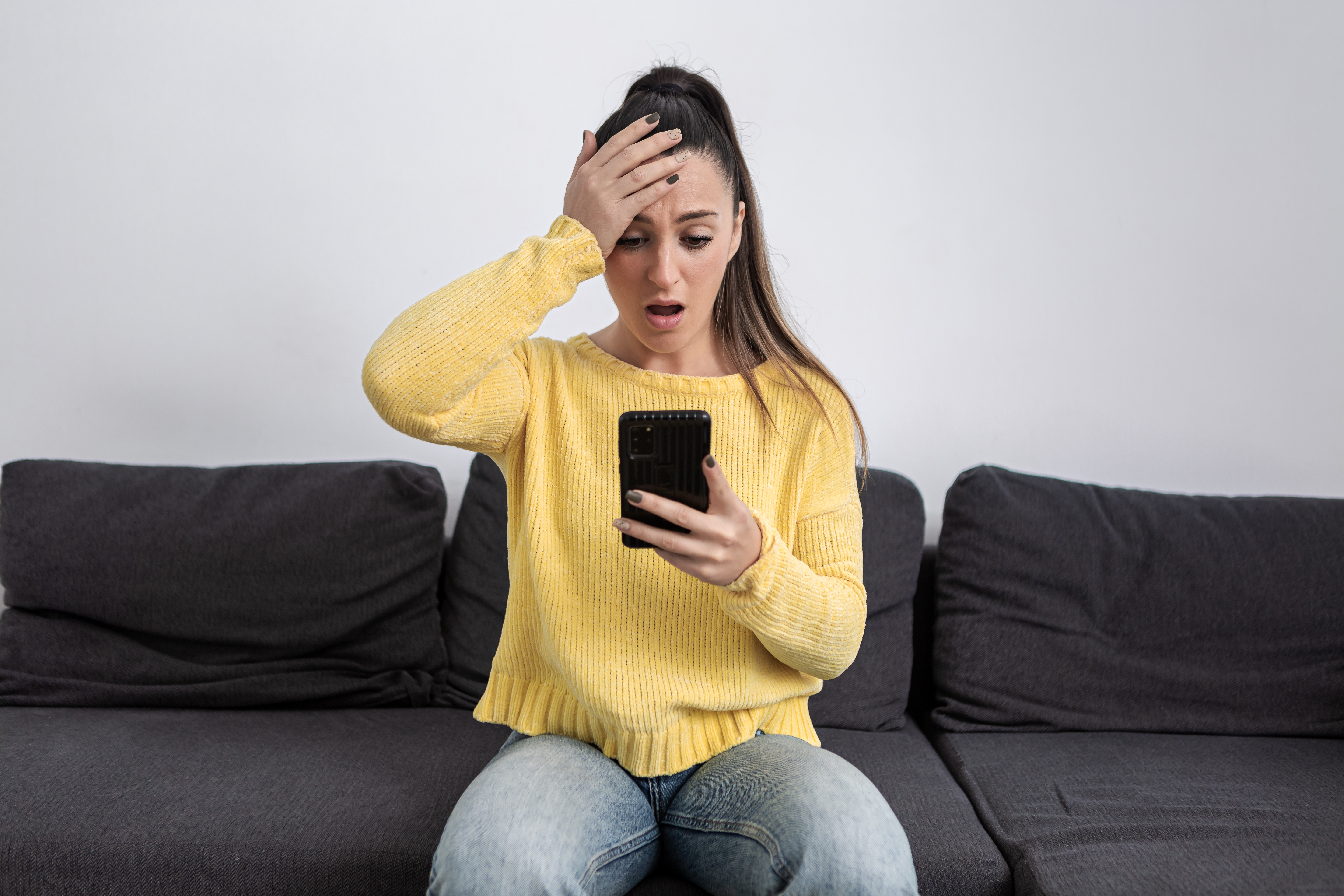 Una mujer queda impactada mientras mira la pantalla de su teléfono móvil | Fuente: Getty Images