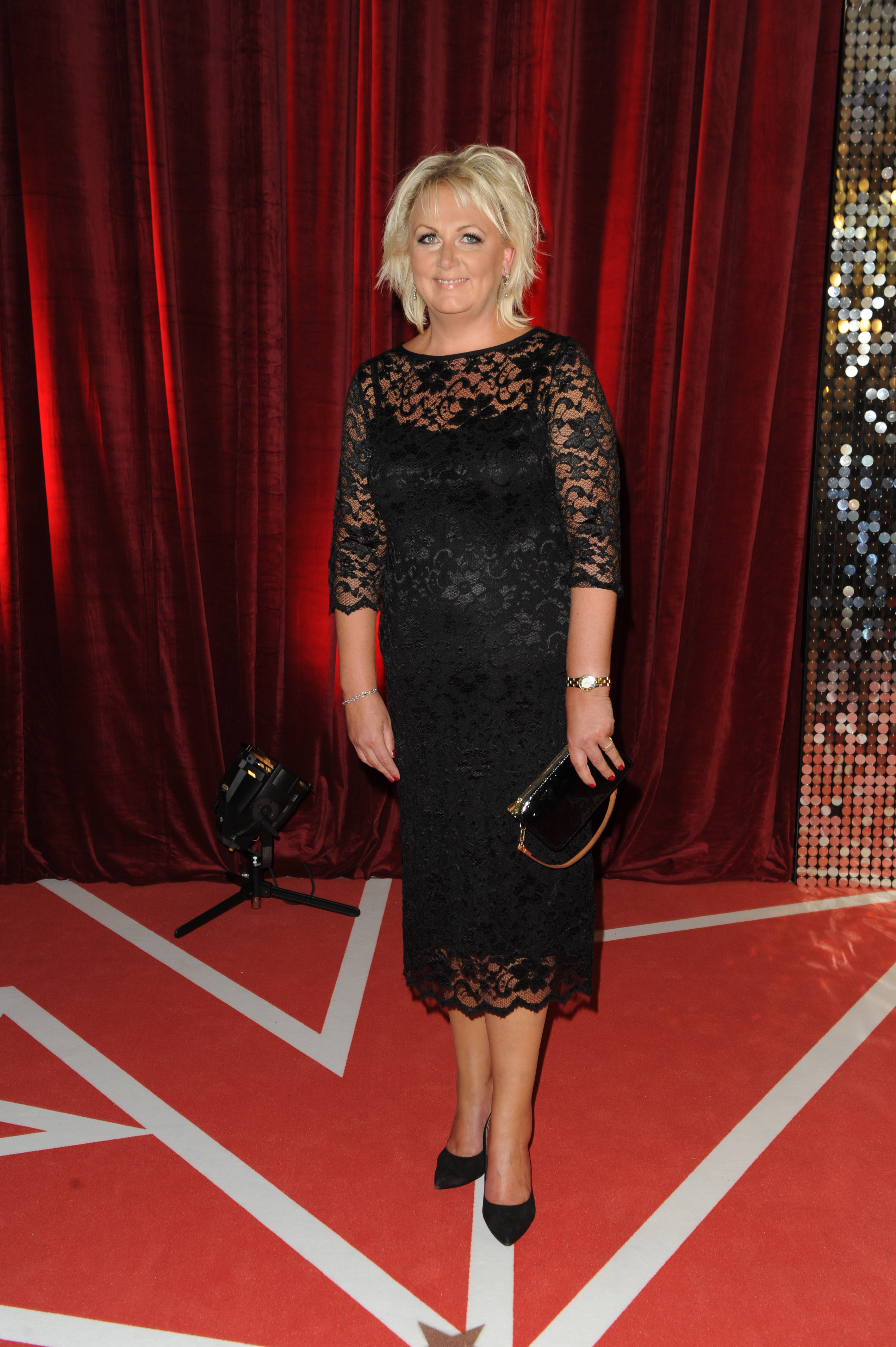 A noticeably more refined Cleaver steps out at the 2013 British Soap Awards in a fitted black lace midi dress with three-quarter sheer sleeves — a polished, body-conscious look that marked a subtle shift in her red carpet style.