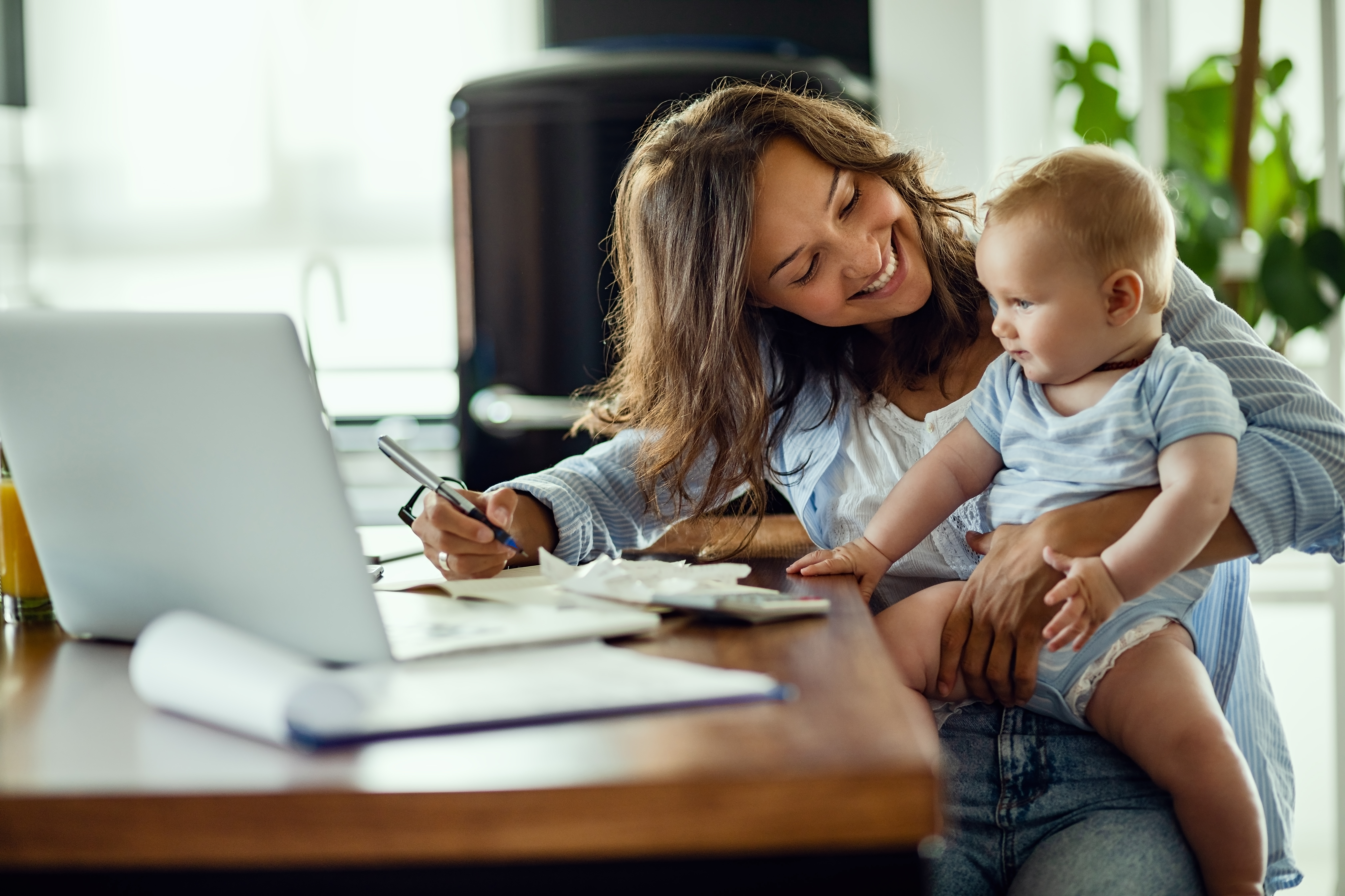 A woman smiling at her child while sitting on a desk | Source: Shutterstock
