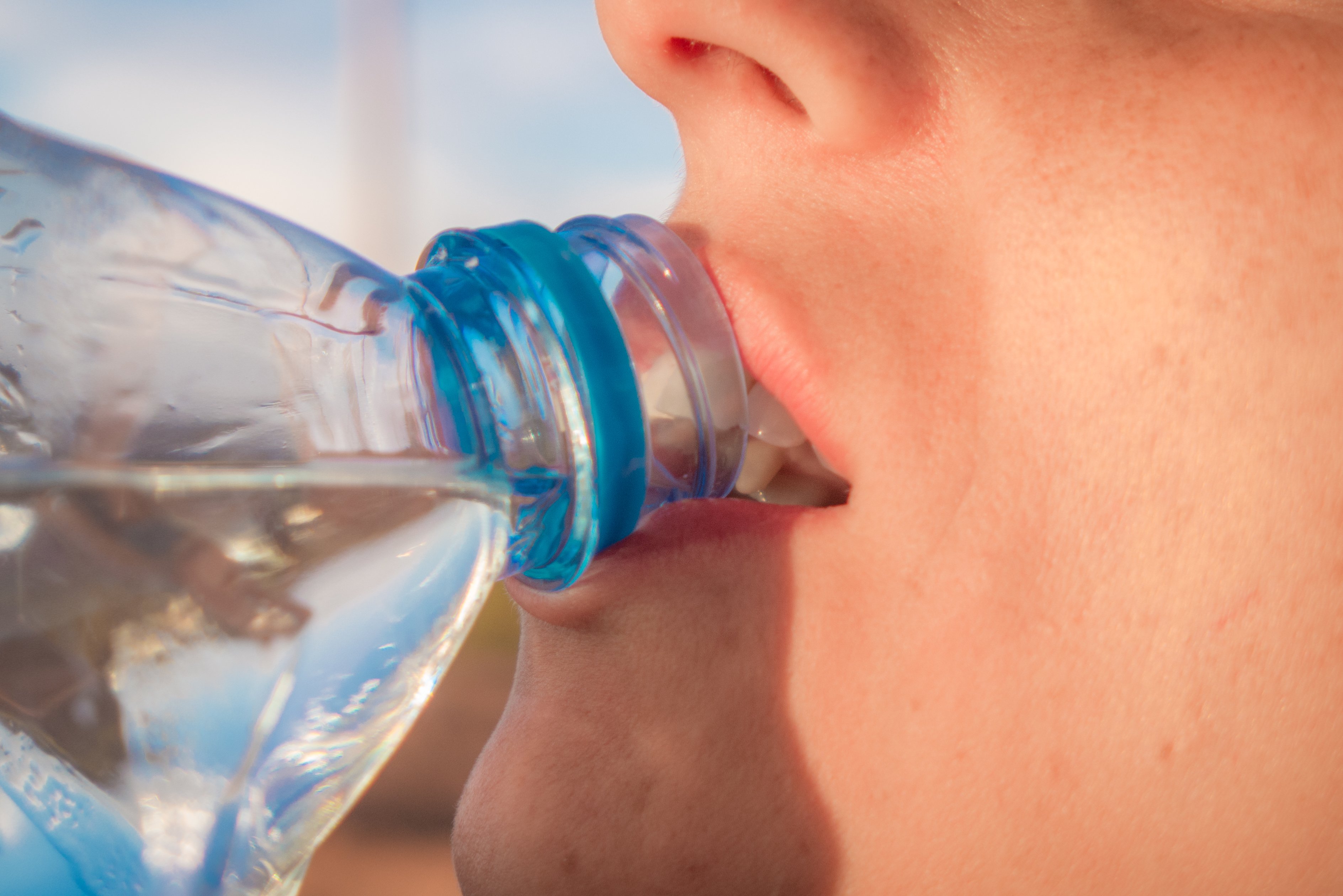 A young man drinking water from a plastic bottle. | Photo: Shutterstock