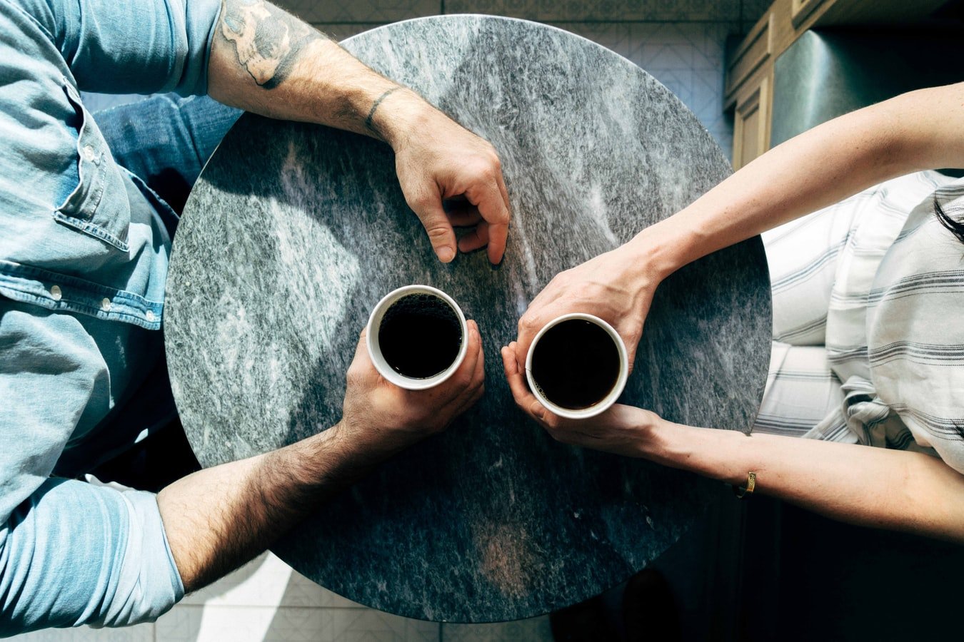 Mann und Frau sitzen mit Kaffe an einem Tisch | Quelle: Unsplash