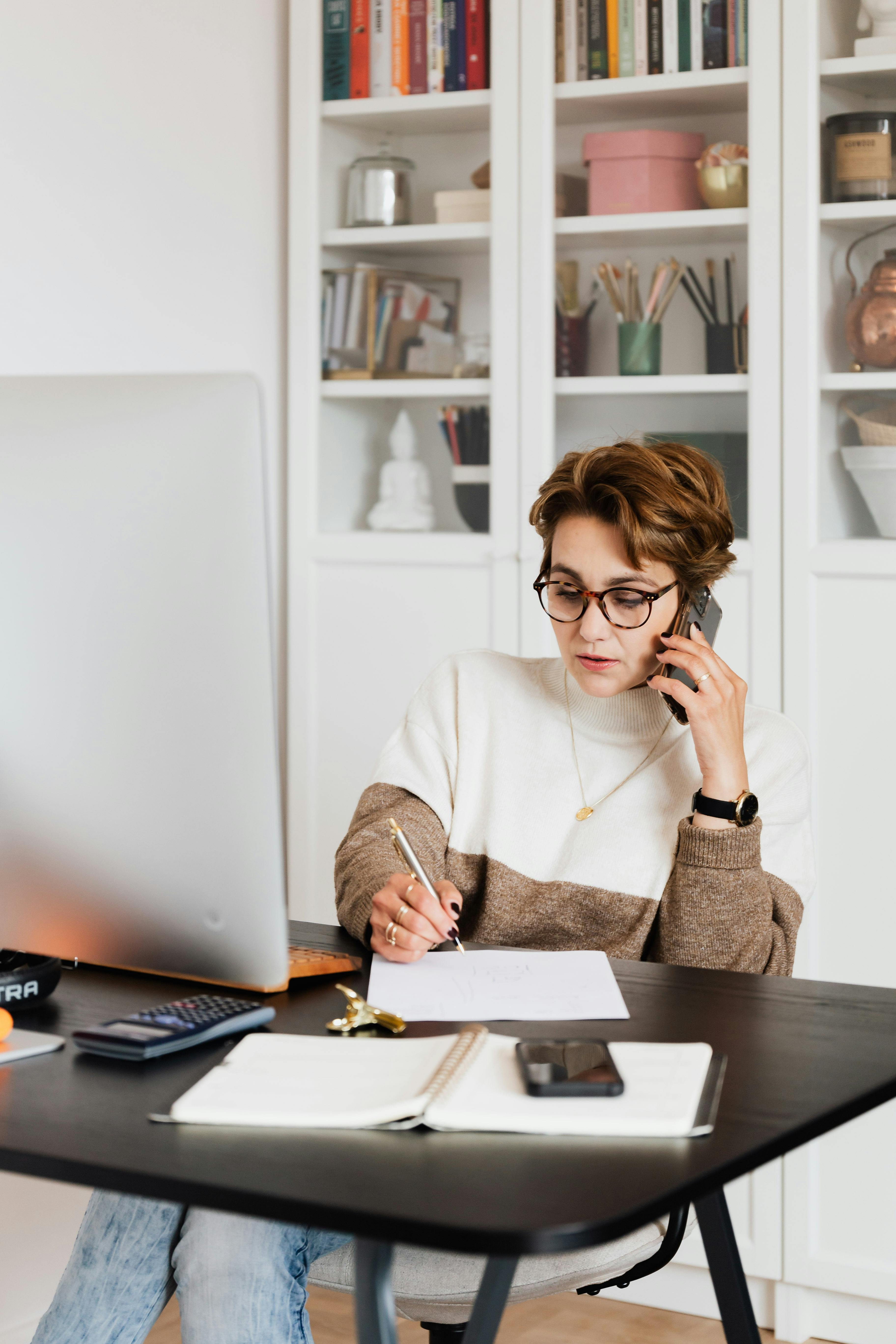 Woman talks on her phone in her office | Source: Pexels