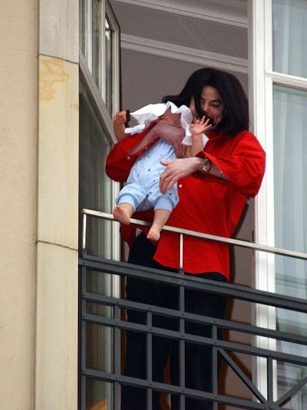 Michael Jackson holds his son eight-month-old son Prince Michael II over the balcony of the Adlon Hotel November 19, 2002, in Berlin, Germany. | Source: Getty Images.
