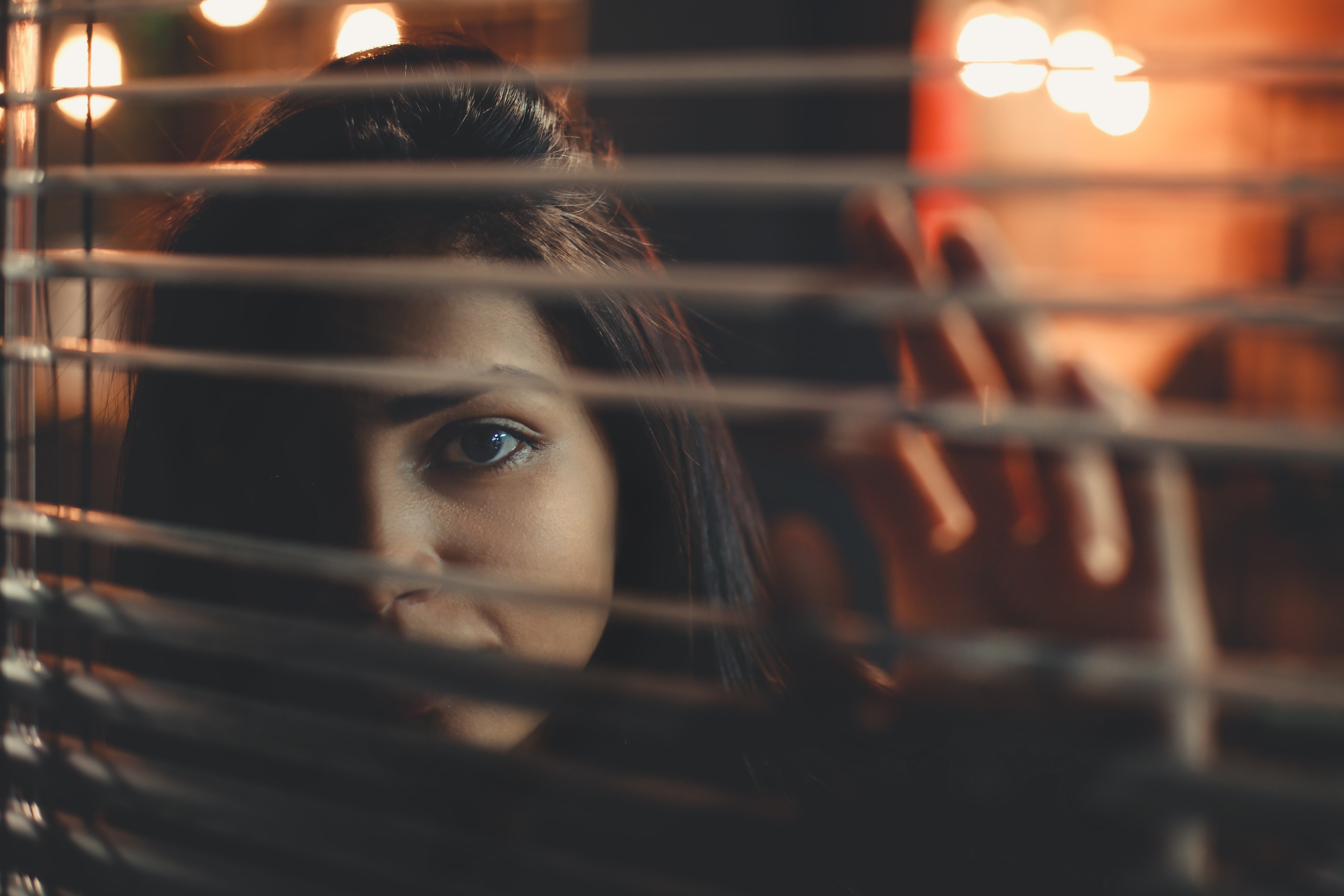 Woman looking through blinds. | Source: Pexels
