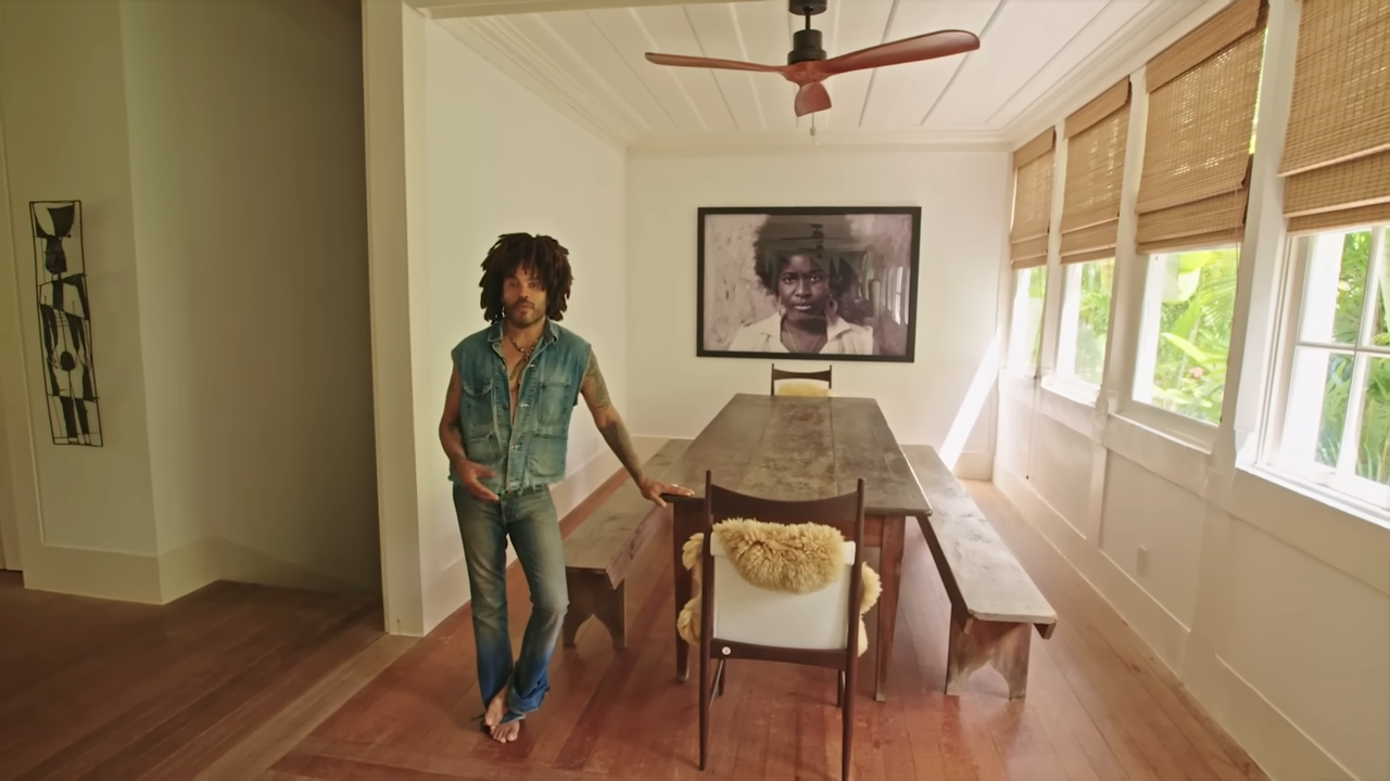 The farmhouse dining area is centered around a long, rustic wooden table with matching bench seating and a large, framed black-and-white portrait of his cousin, Janelle, from the Bahamas. | Source: YouTube/@Archdigest