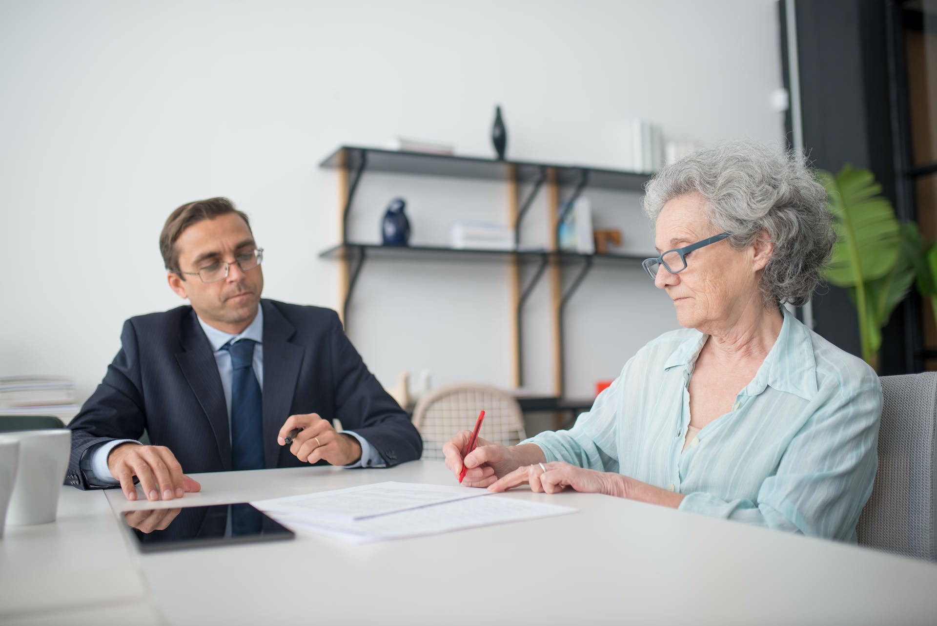 Elderly woman signing documents in a workplace | Source: Pexels