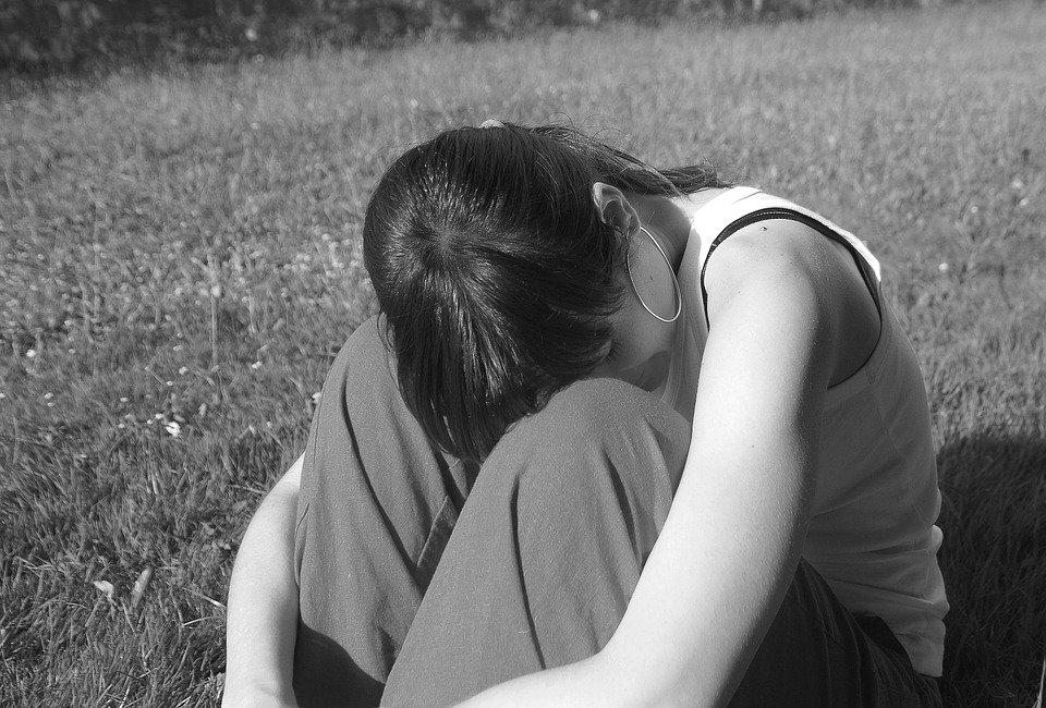 Verzweifelte Frau sitzt im Gras | Quelle: Pixabay