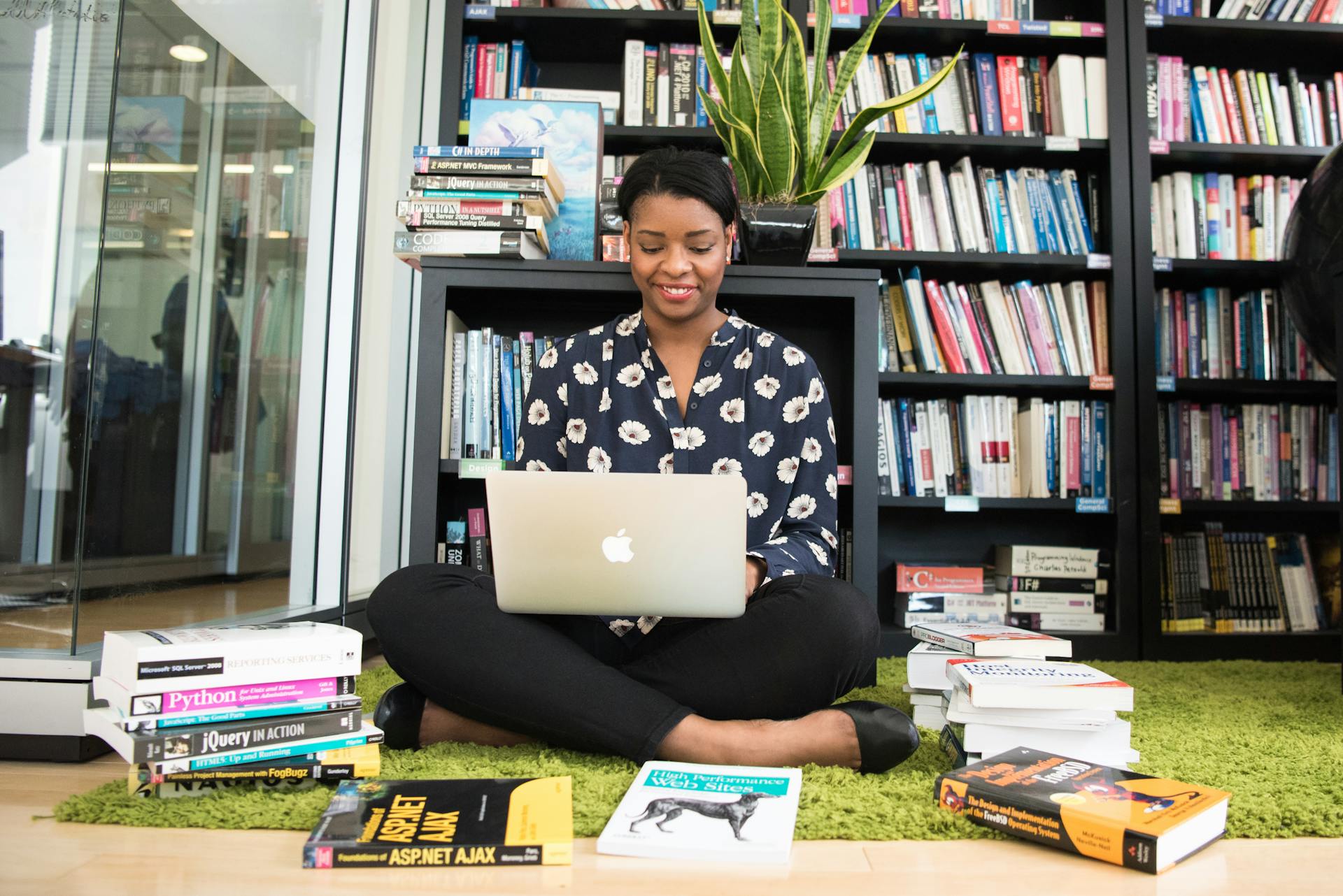 A woman browsing her laptop while sitting in a library | Source: Pexels