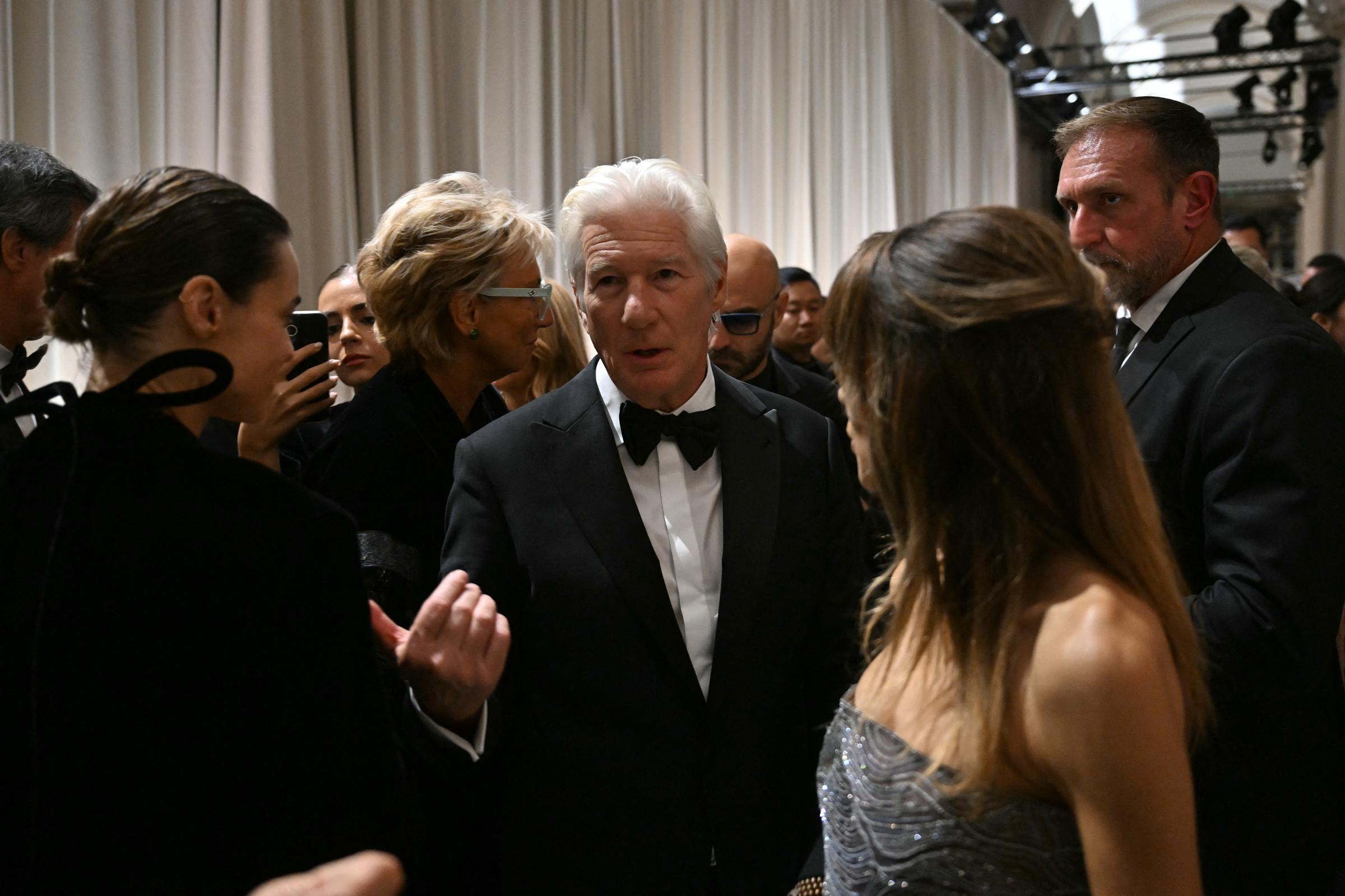 In a candid moment post-show, Richard Gere speaks animatedly with Kasia Smutniak while Alejandra Silva listens in — elegance and intensity woven into every glance.