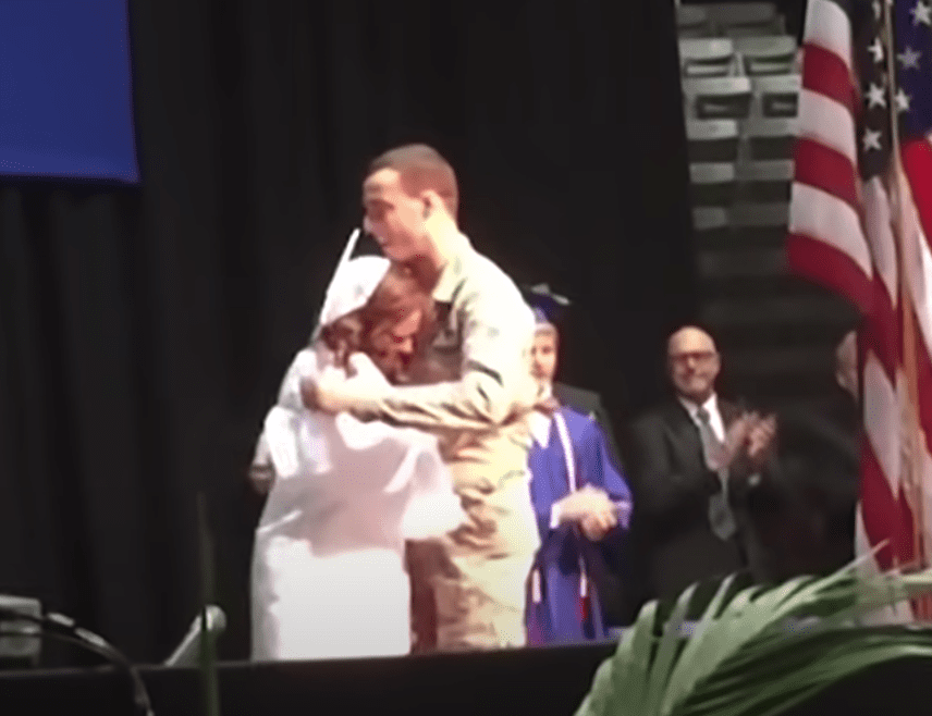 A brother and sister embrace after he returned from the military to surprise her at her graduation | Photo: Youtube/USA TODAY