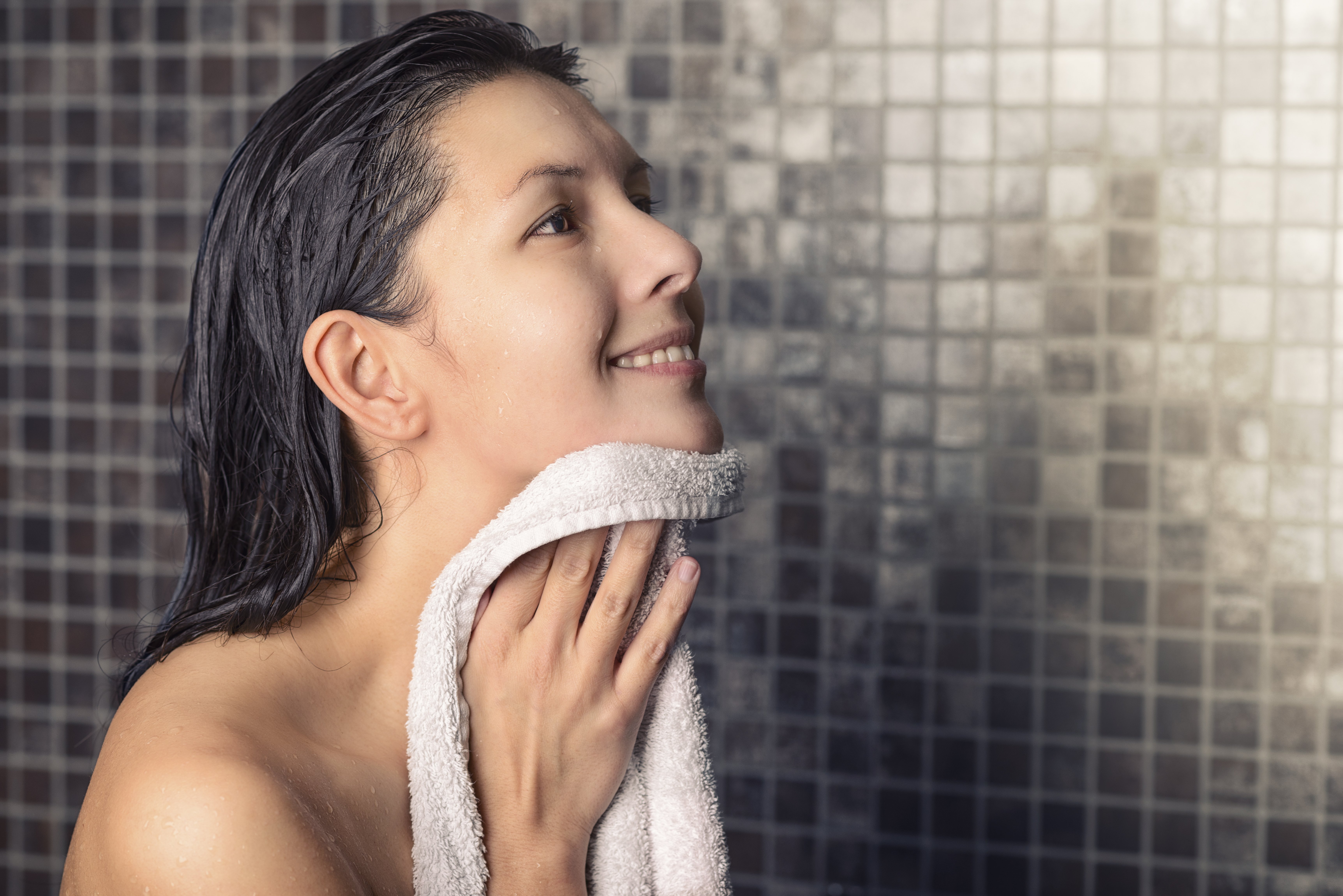 Une femme sous la douche avec une serviette. | Photo : Shutterstock