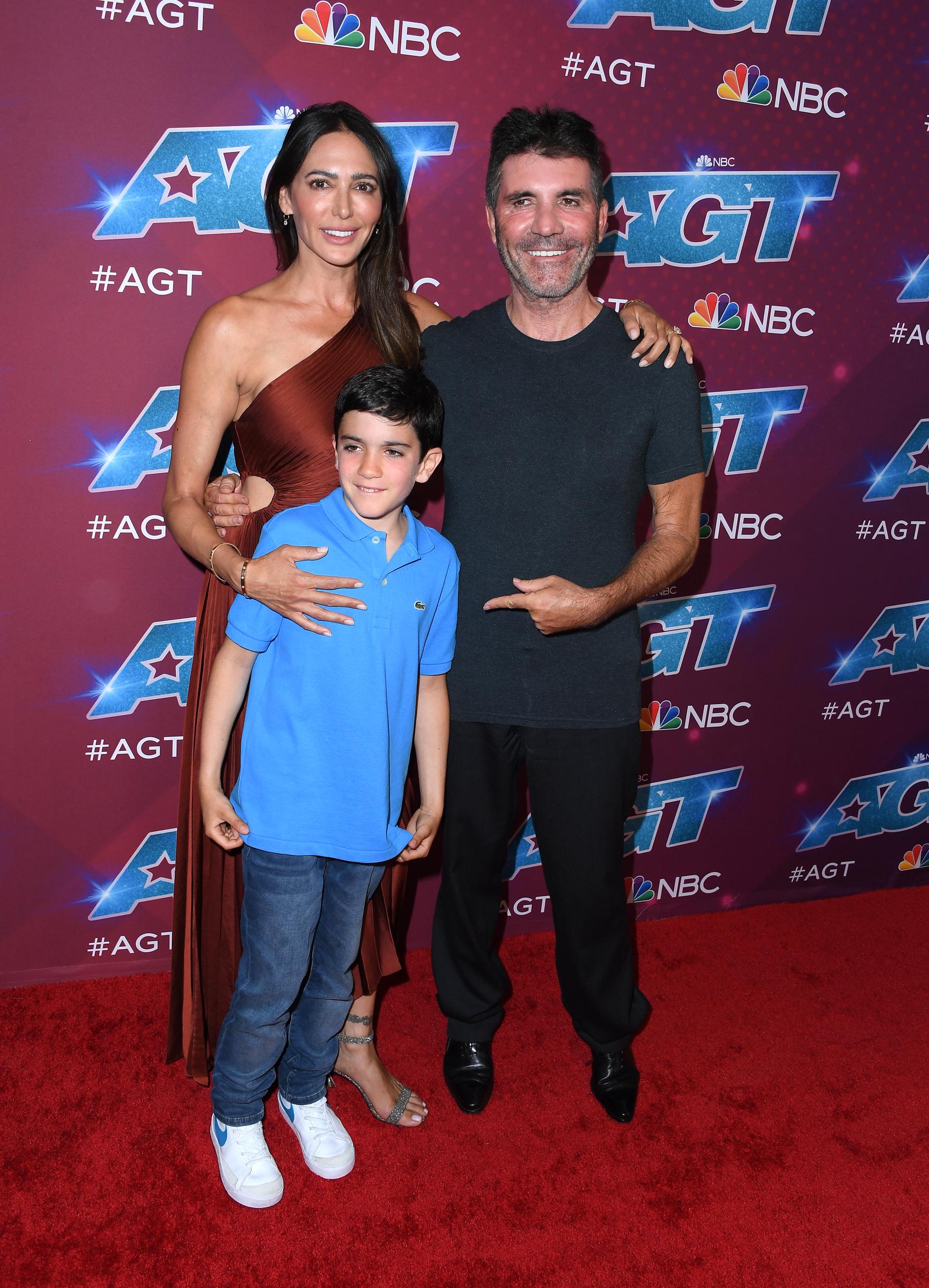Eric, growing into a fine young boy, stands with his parents, Lauren Silverman and Simon Cowell, at the red carpet for "America's Got Talent" Season 17 Live Show at the Sheraton Pasadena Hotel in Pasadena, California. All three smile warmly, capturing a perfect family moment.