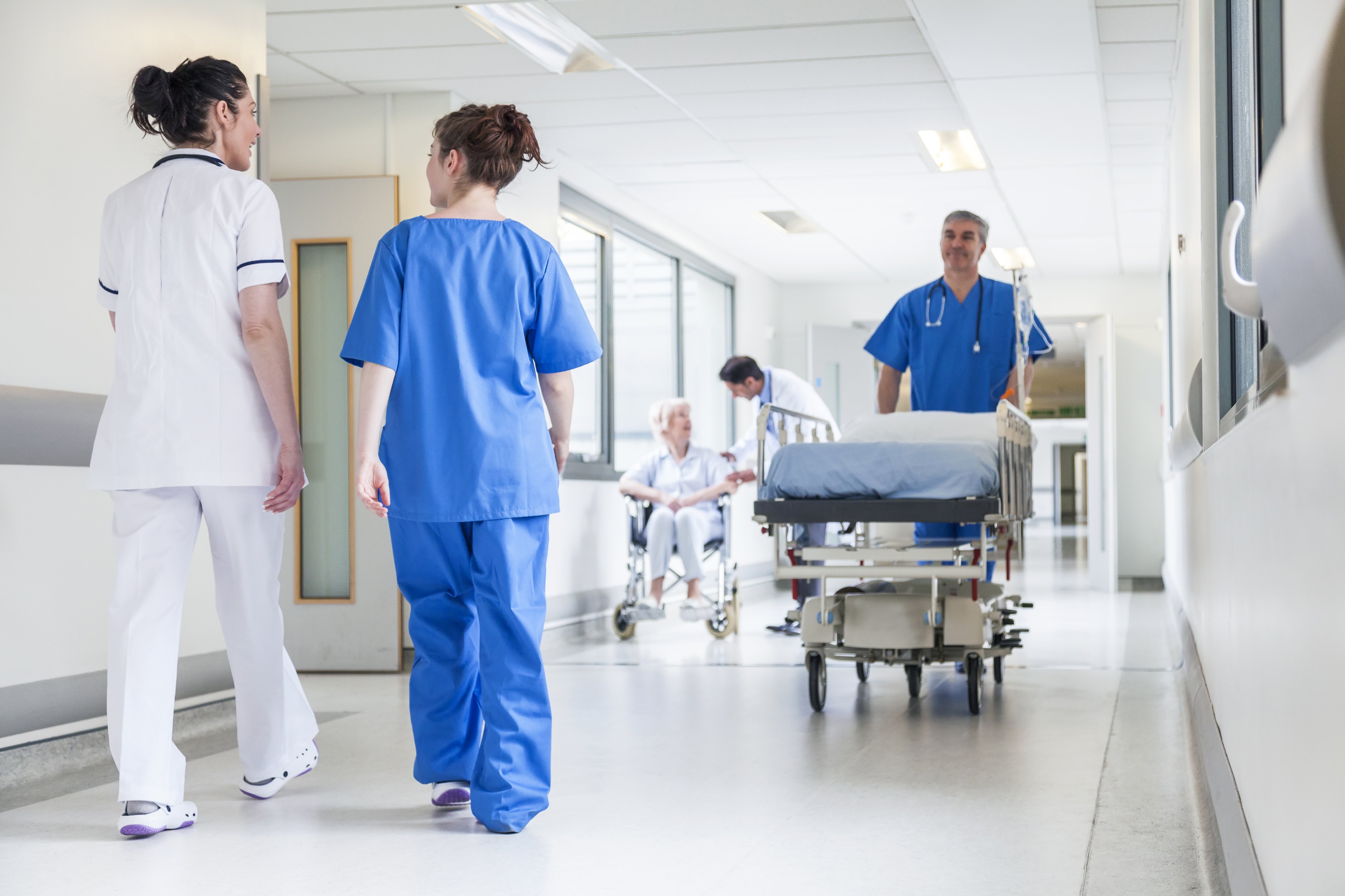 Hombre trasladando camilla en pasillo de hospital, rodeado de personal médico. | Imagen: Shutterstock Hombre trasladando camilla en pasillo de hospital, rodeado de personal médico. | Imagen: Shutterstock