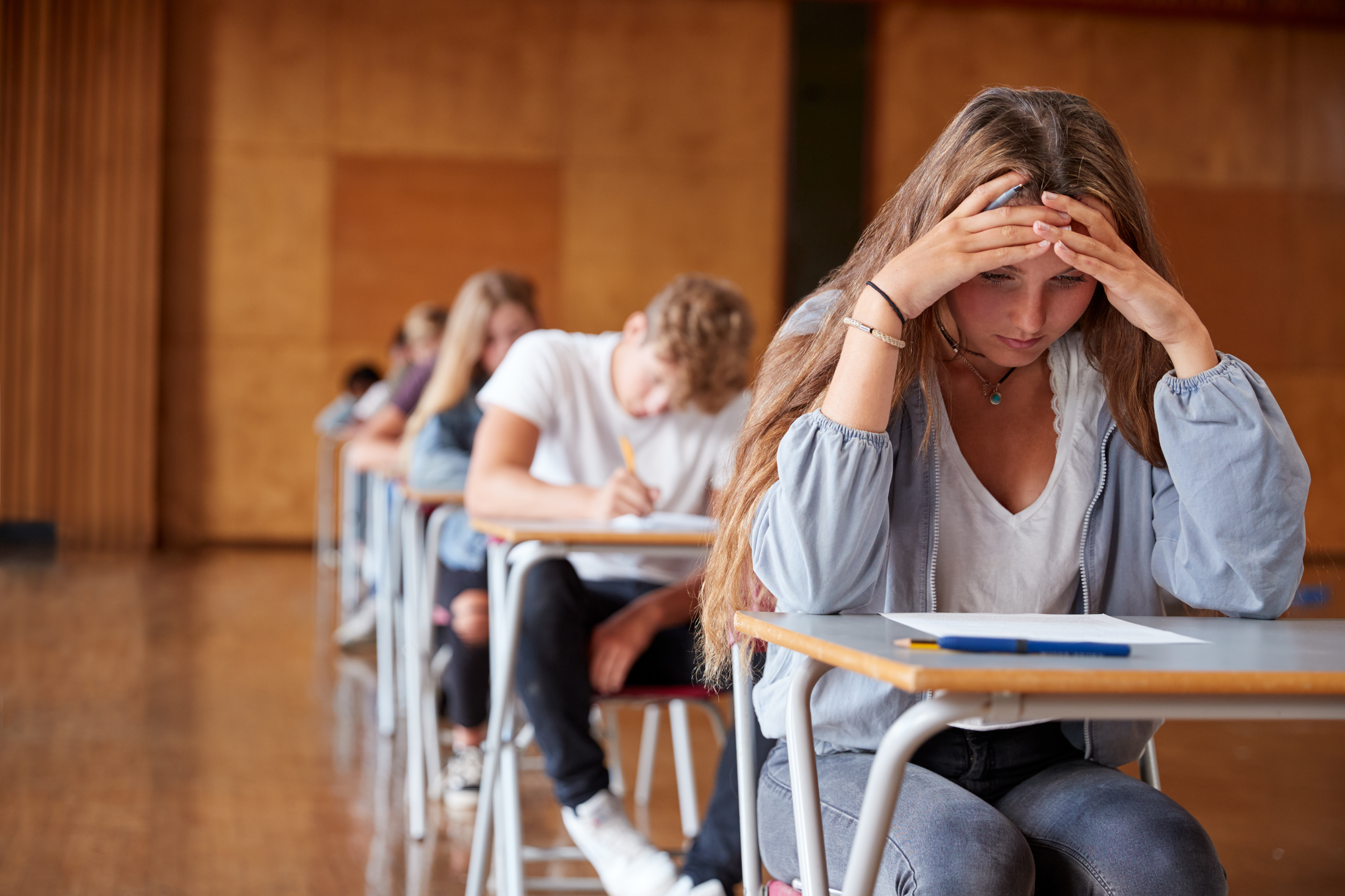 A stressed girl sitting in an examination hall with other students | Source: Shutterstock