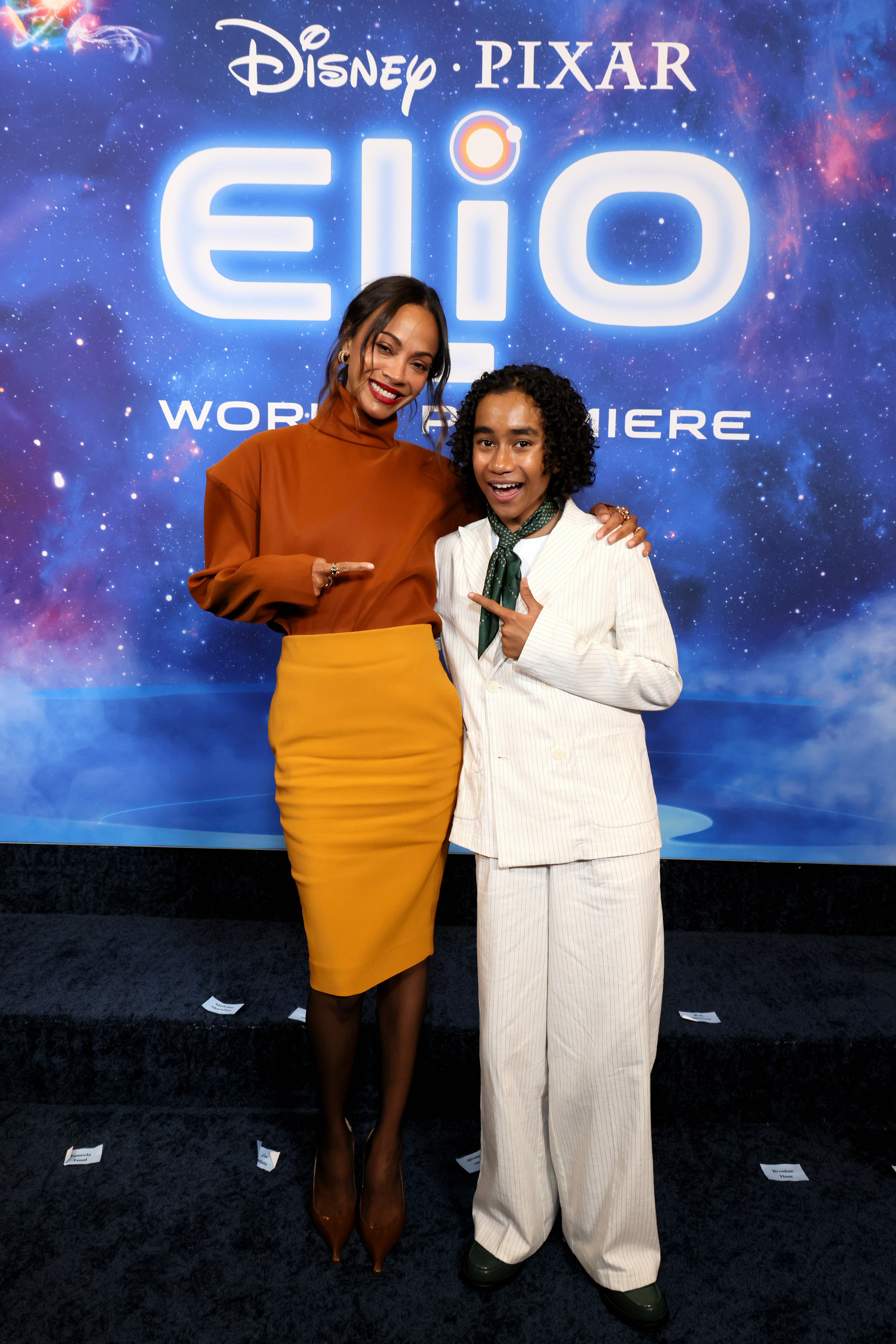 Zoe Saldaña and Yonas Kibreab point at each other in a playful pose while they smile at the camera at the El Capitan Theater.