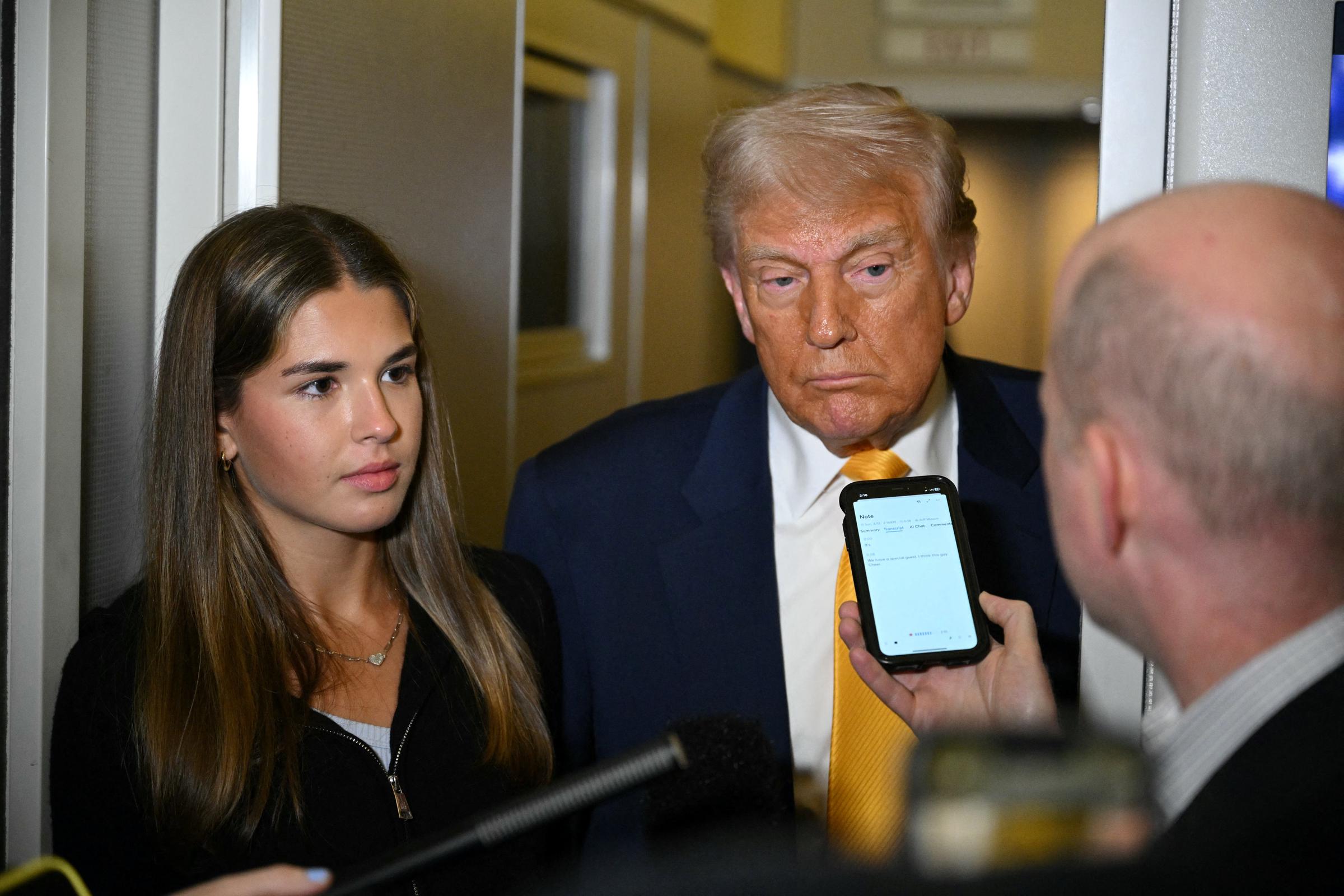 Donald Trump listens to reporters as his granddaughter Kai Madison Trump looks on on board Air Force One while flying from Miami to Palm Beach on April 13, 2025 | Source: Getty Images