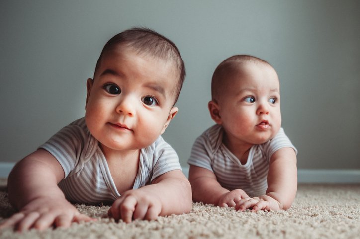 7 Month Old Male Fraternal Twins Sit On Carpet Lit by Softbox | Photo: Getty Images