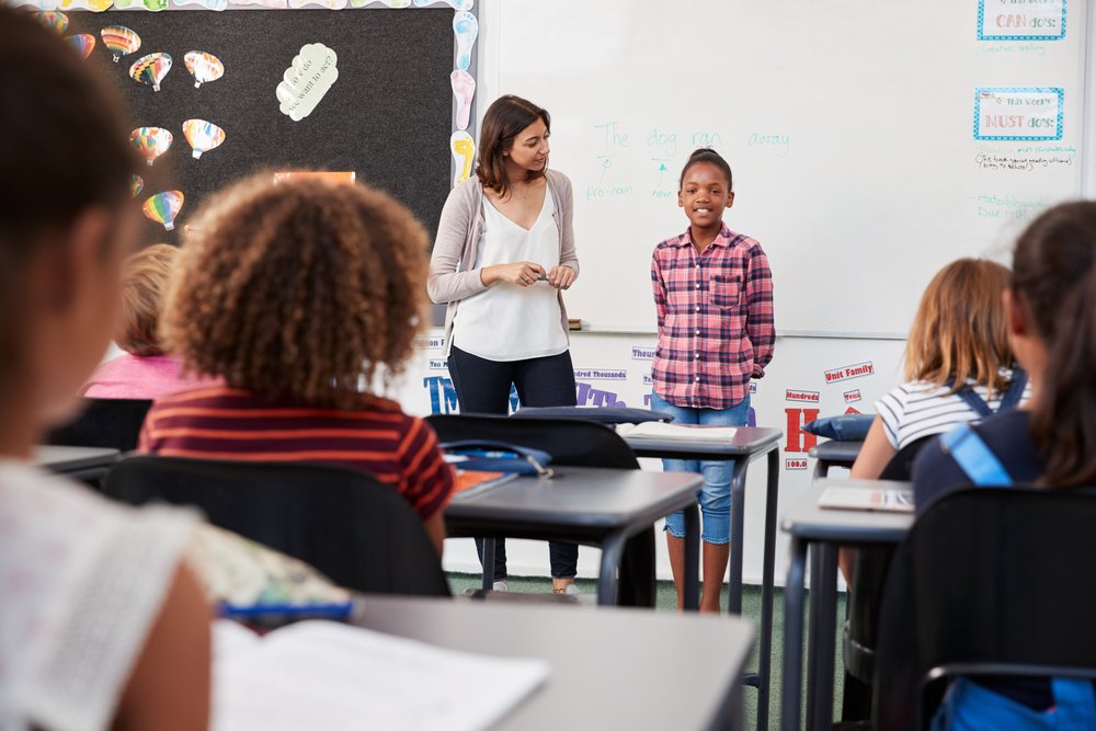 A teacher and pupil in front of elementary school class. | Photo: Shutterstock