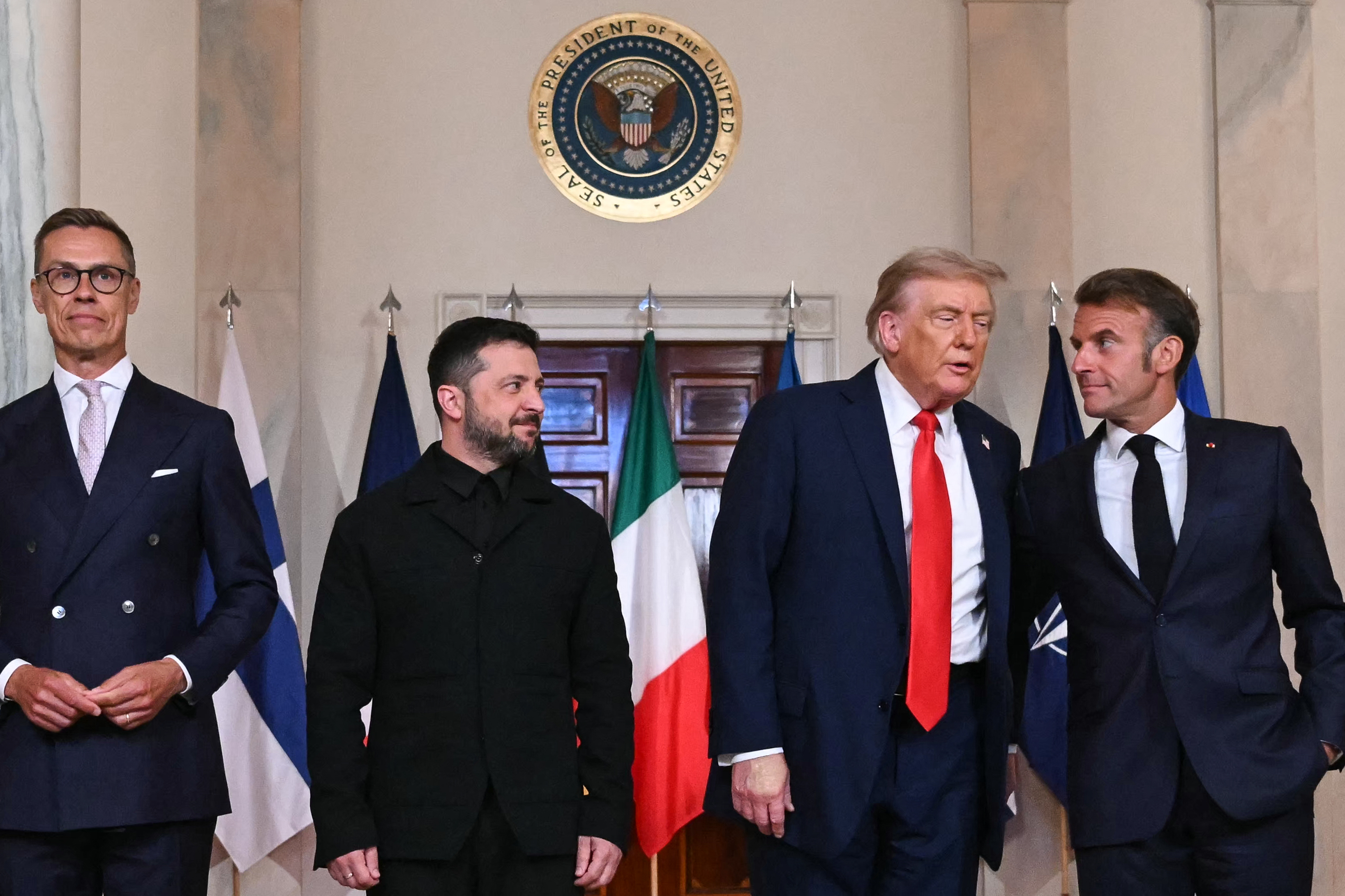 Ukrainian President Volodymyr Zelensky,   US President Donald Trump, Finnish President Alexander Stubb, and French President Emmanuel Macron stand for photos in the Cross Hall of the White House in Washington, DC, on August 18, 2025 | Source: Getty Images