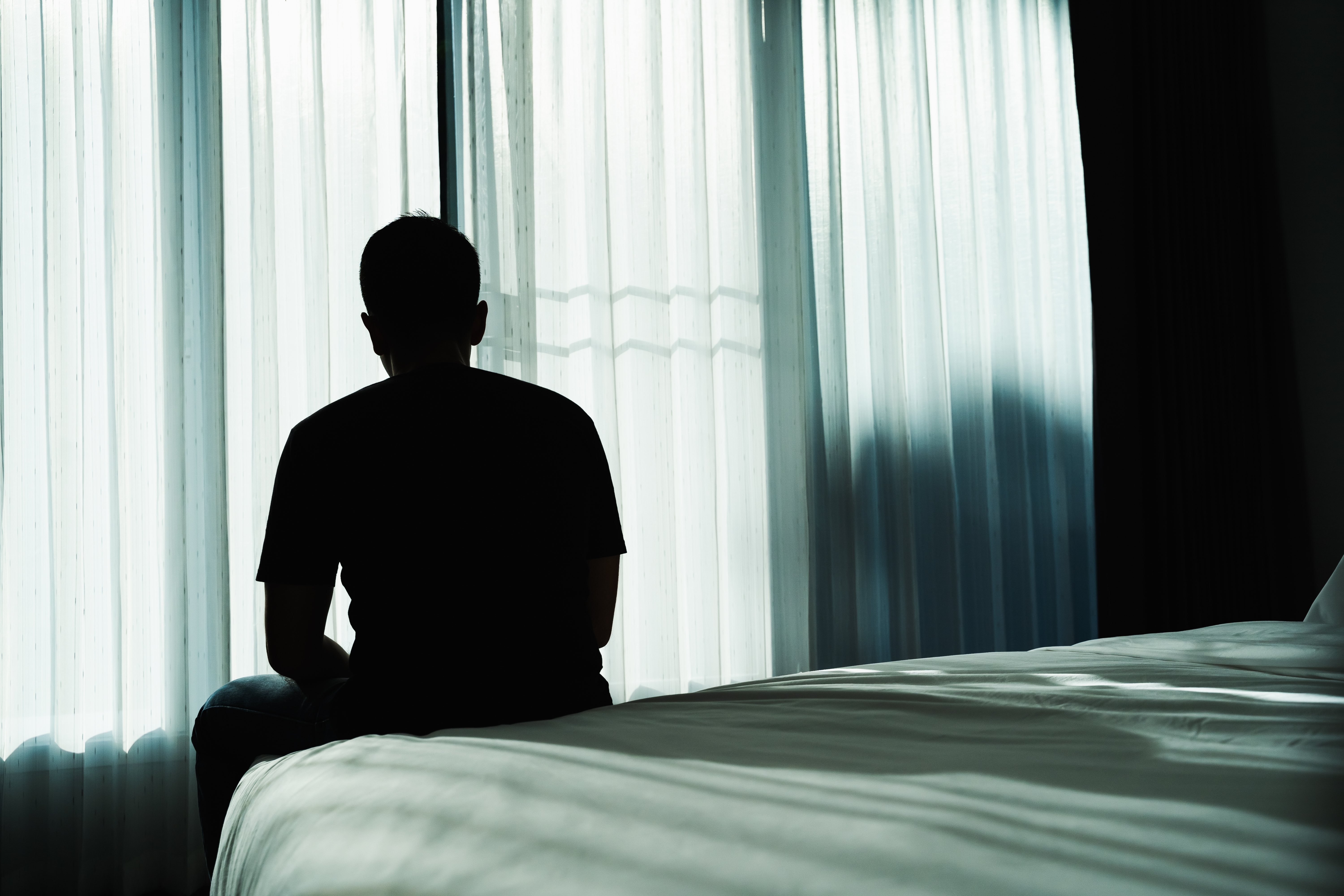 Silhouette of a man sitting on a bed | Source: Shutterstock
