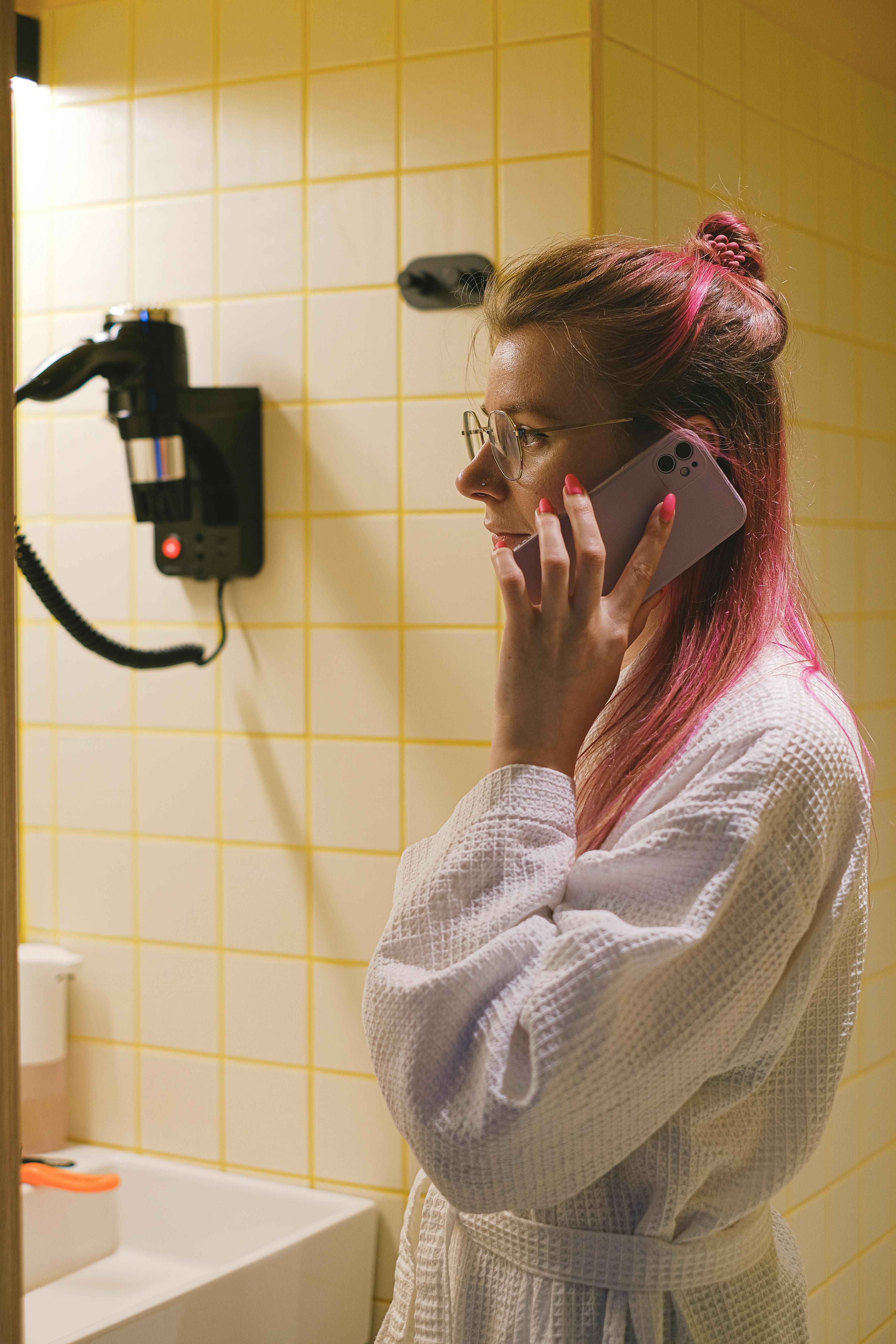 A woman talking on a phone in a bathroom | Source: Pexels