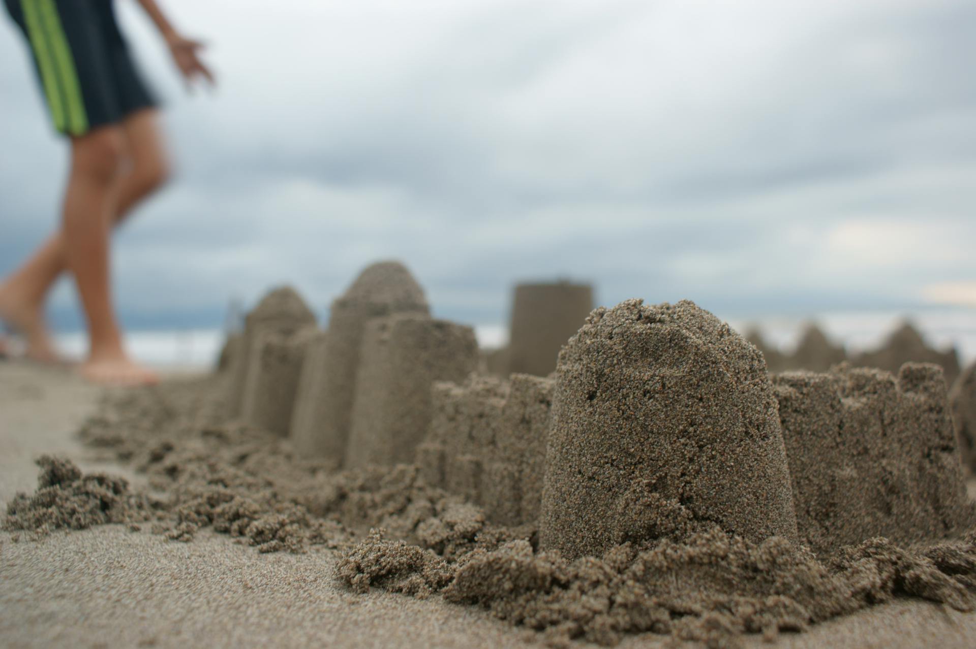 Uma criança parada perto de um castelo de areia | Fonte: Pexels