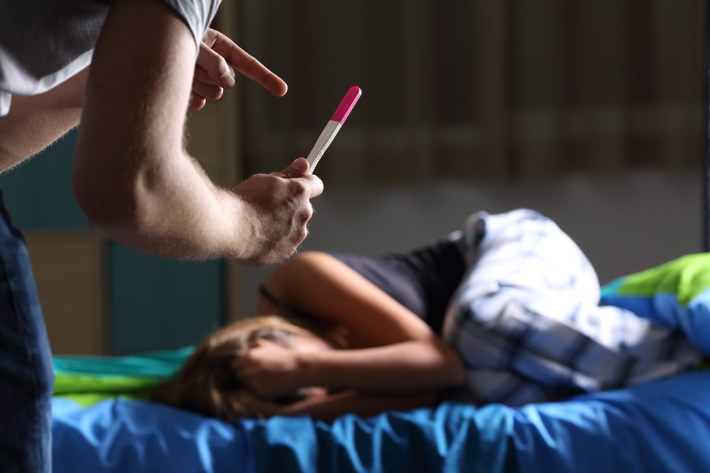 Father asking for explanation showing pregnancy test to a sad pregnant teen | Photo: Shutterstock