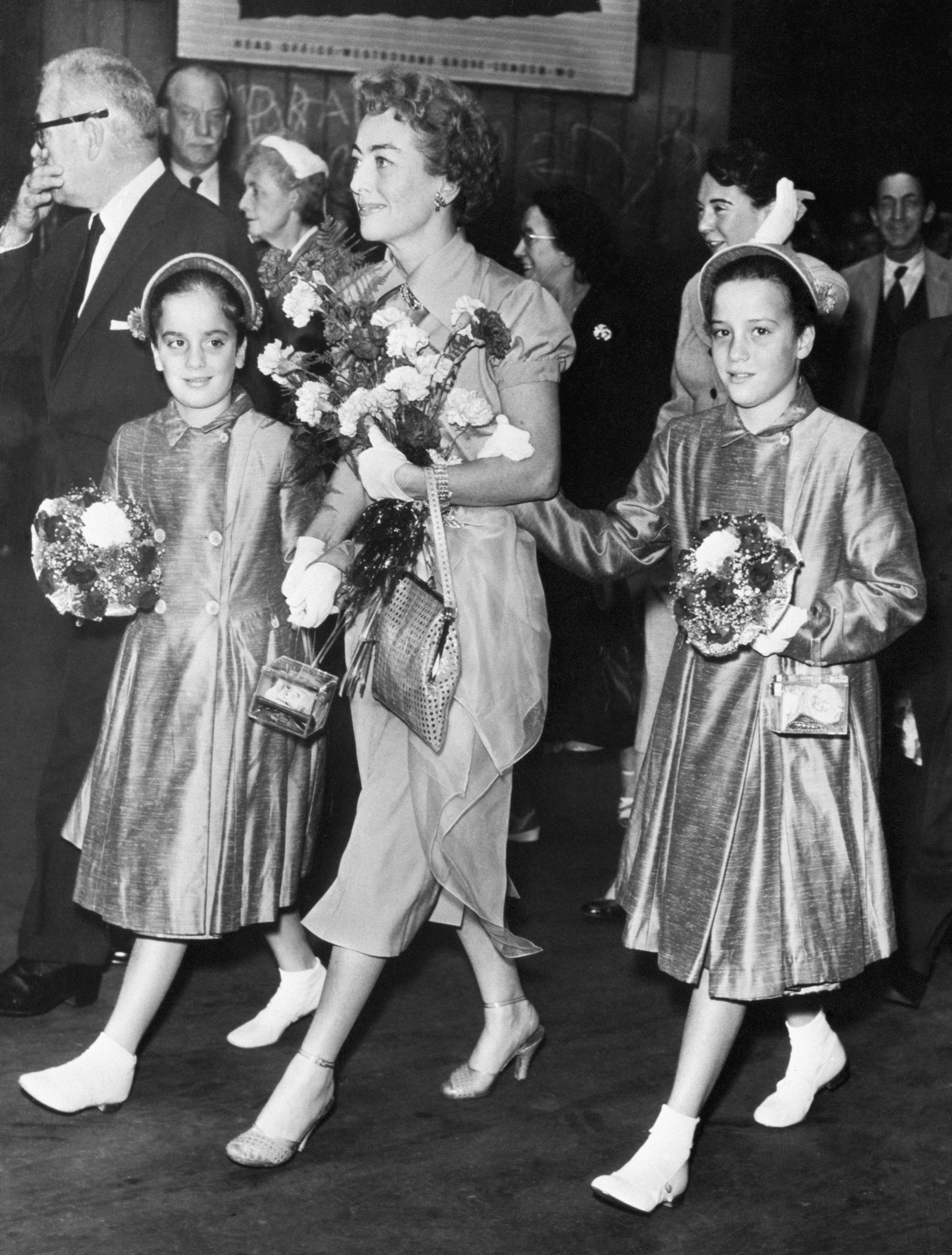 Hollywood actress Joan Crawford strides along the platform of London's Paddington Station with her adopted twin daughters, Cynthia (right) and Cathy, 8/3/56-London, England: | Source: Getty Images