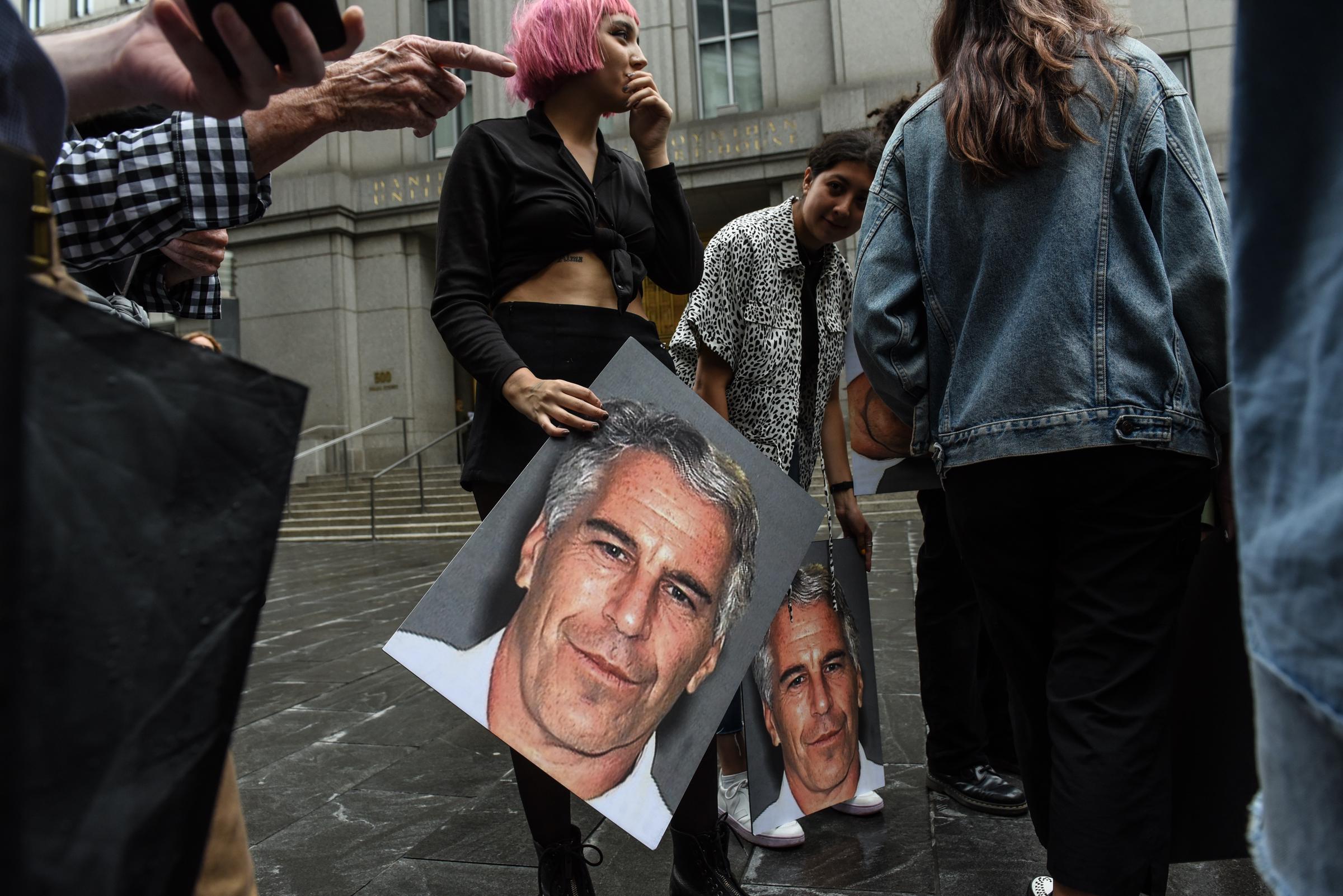 A protest group called "Hot Mess" hold up signs of Jeffrey Epstein in front of the Federal courthouse on July 8, 2019 in New York City. | Source: Getty Images