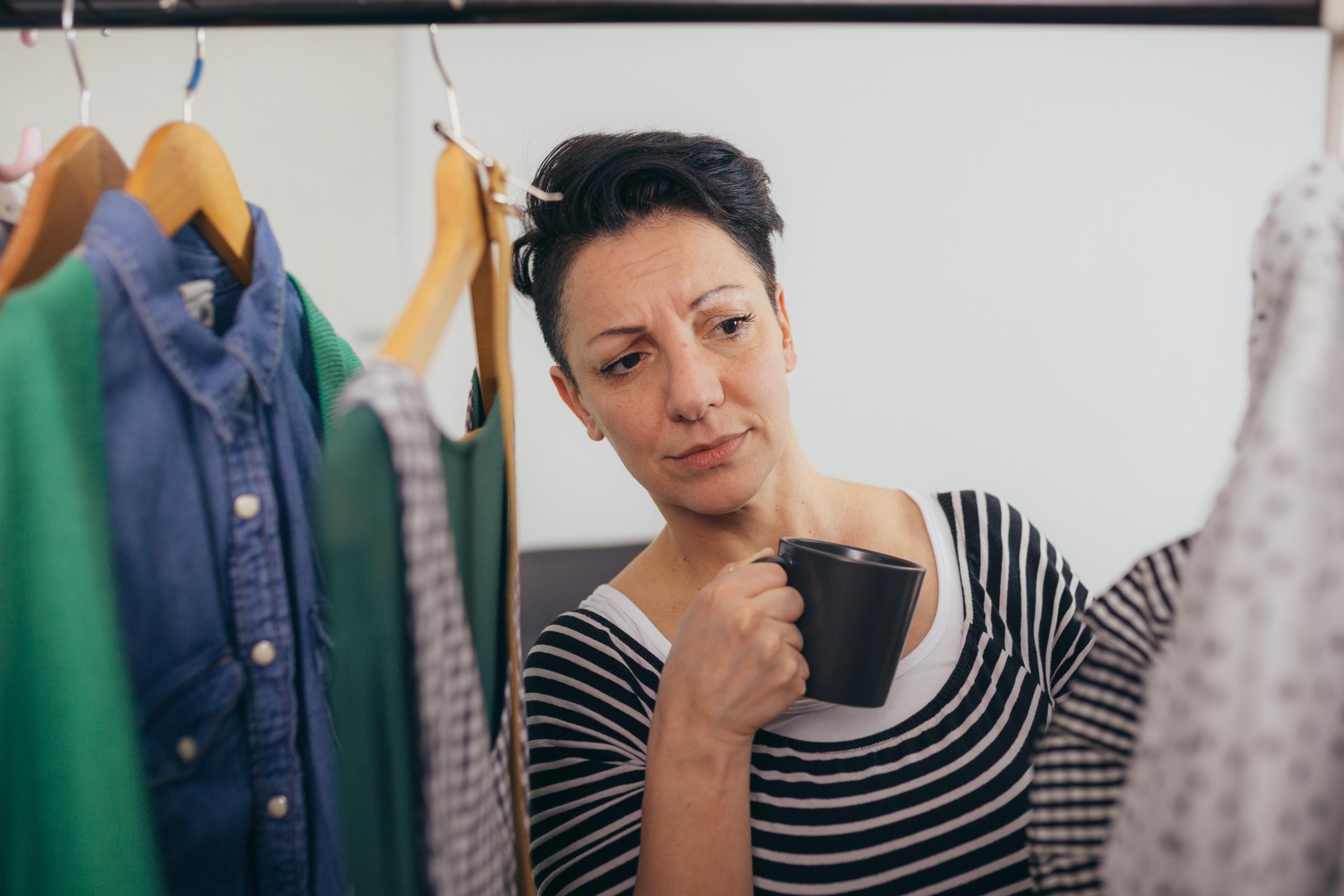 Woman frowning at her clothes in her closet | Source: Shutterstock