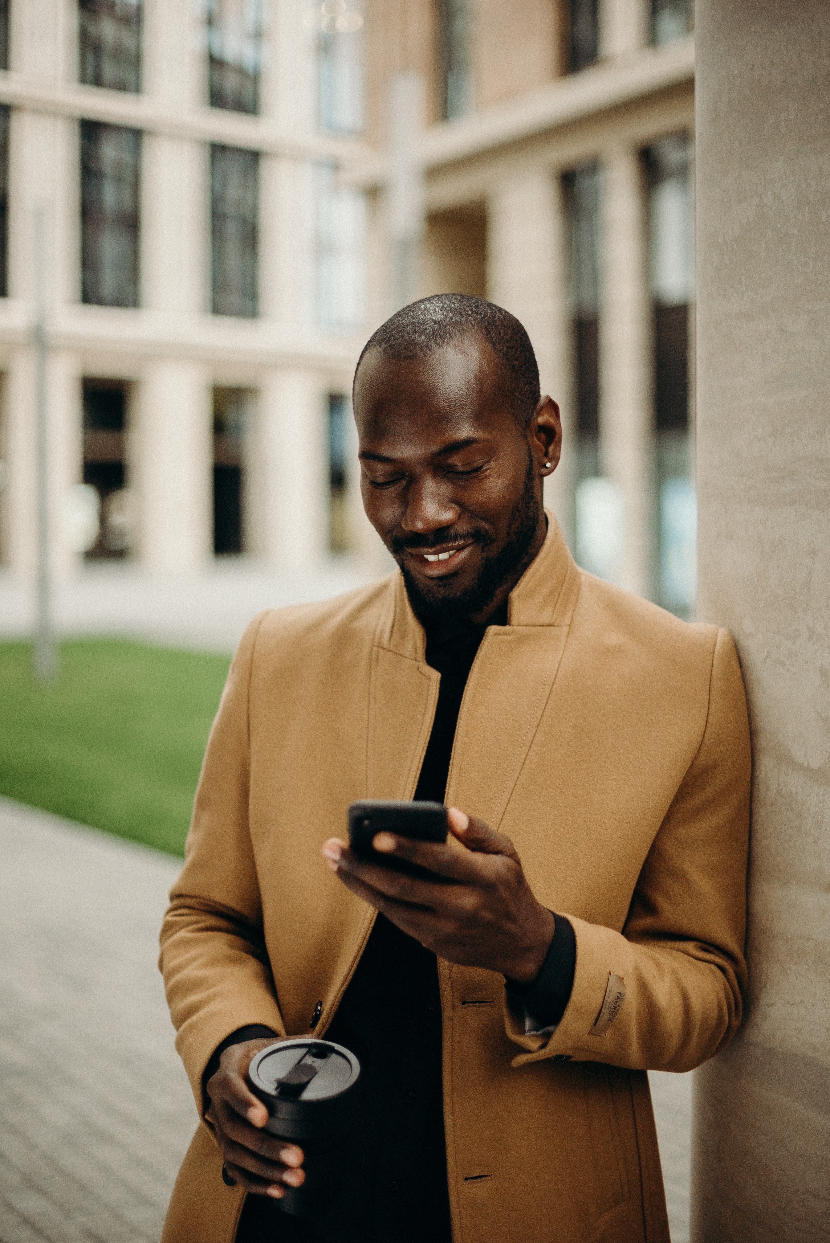 A man holding a coffee mug while looking at his phone. | Source: Pexels