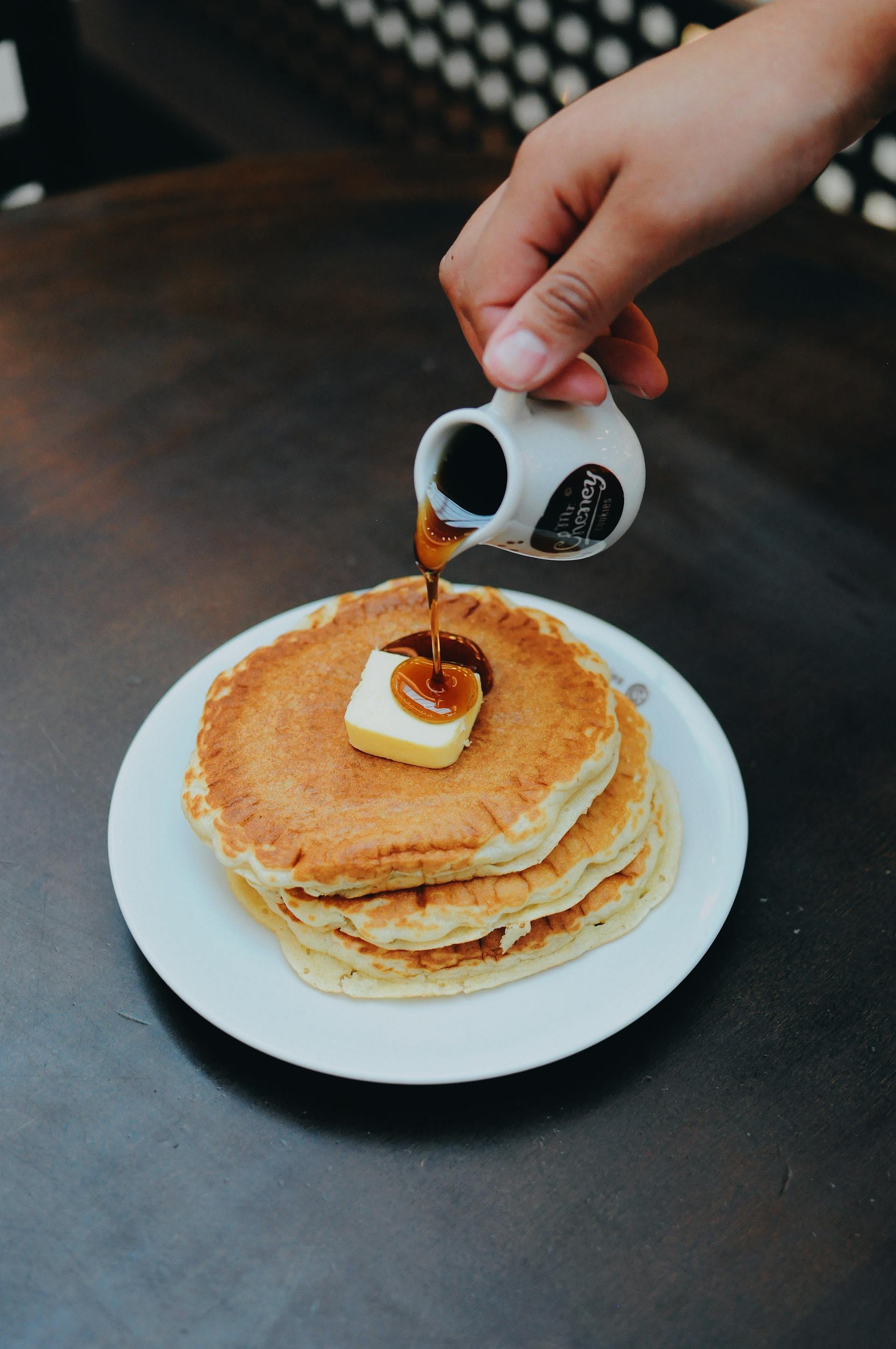 A person pouring syrup on pancakes | Source: Pexels